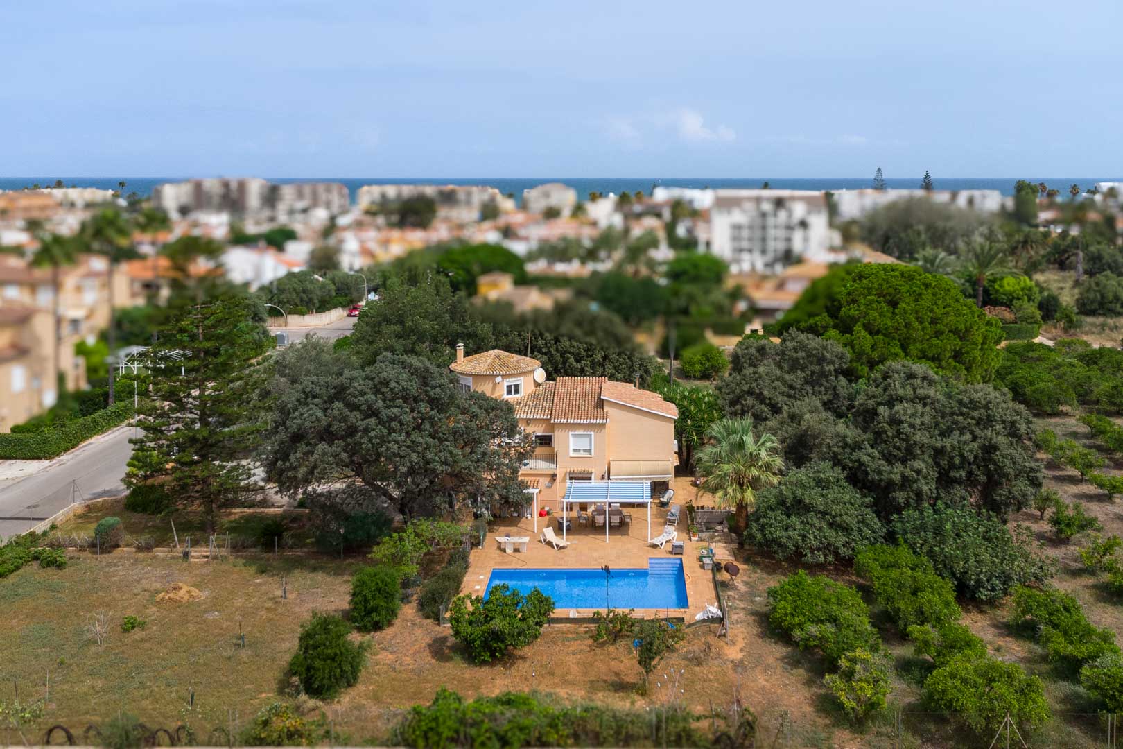 Aerial view of the Mediterranean villa in Las Marinas, featuring a large flat plot with a swimming pool, shaded terraces, and sea views in the distance.