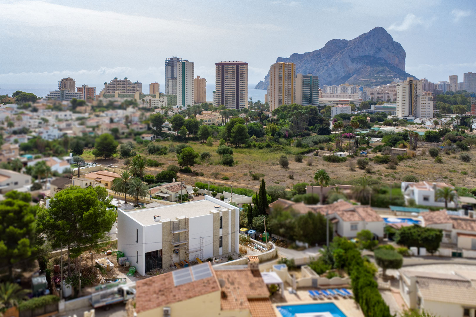 Aerial perspective of the villa under construction, showcasing the stone exterior details and the panoramic views of the Peñón de Ifach and Calpe skyline.
