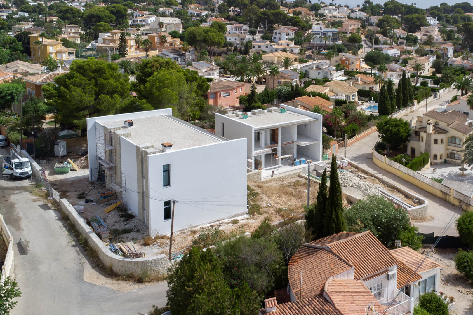 Aerial view of the construction phase, showcasing the modern structure with white walls and natural stone details in the La Merced area.