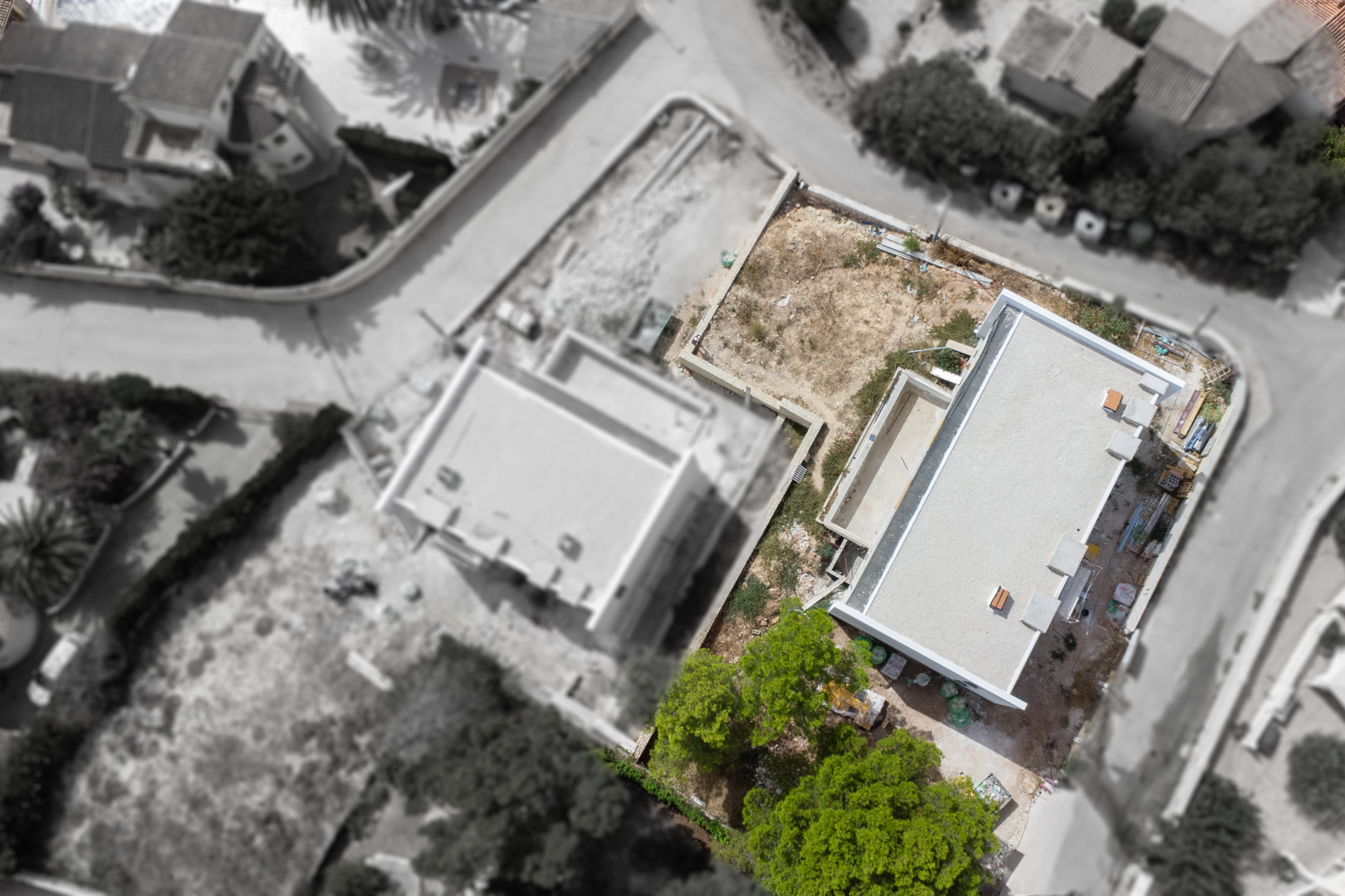 Aerial view showing the construction progress of the villa's structure, the pool area, and the layout of the flat plot in Calpe.