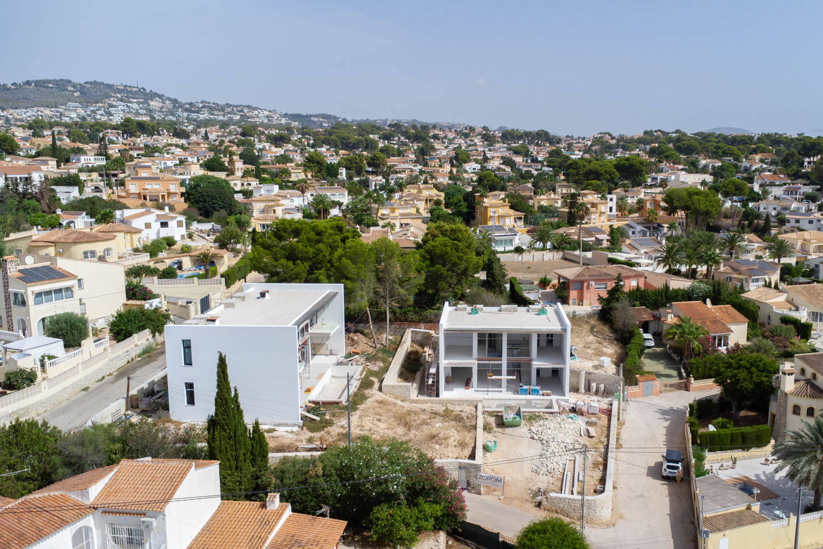 Aerial view of the modern two-story villa under construction, highlighting the white facade and flat plot within the residential landscape of Calpe.