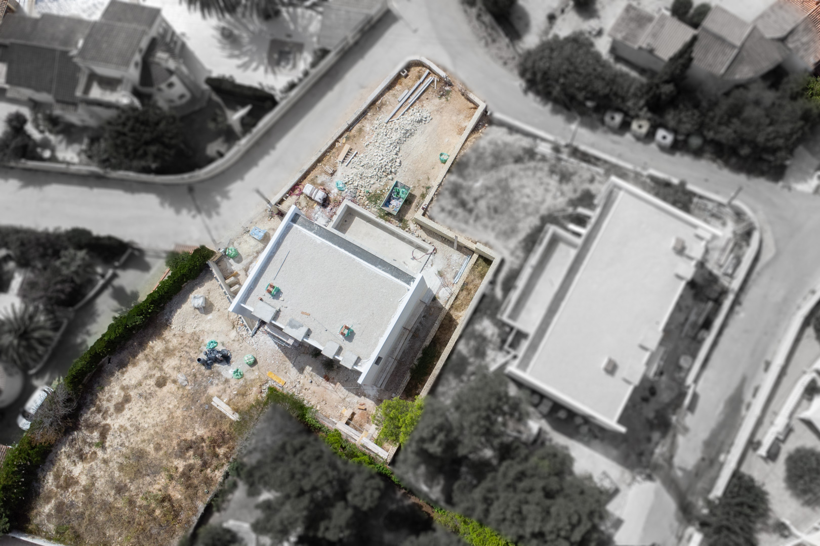 Aerial view showing the construction progress of the villa's structure on a flat plot, highlighting the building's footprint within the residential area.