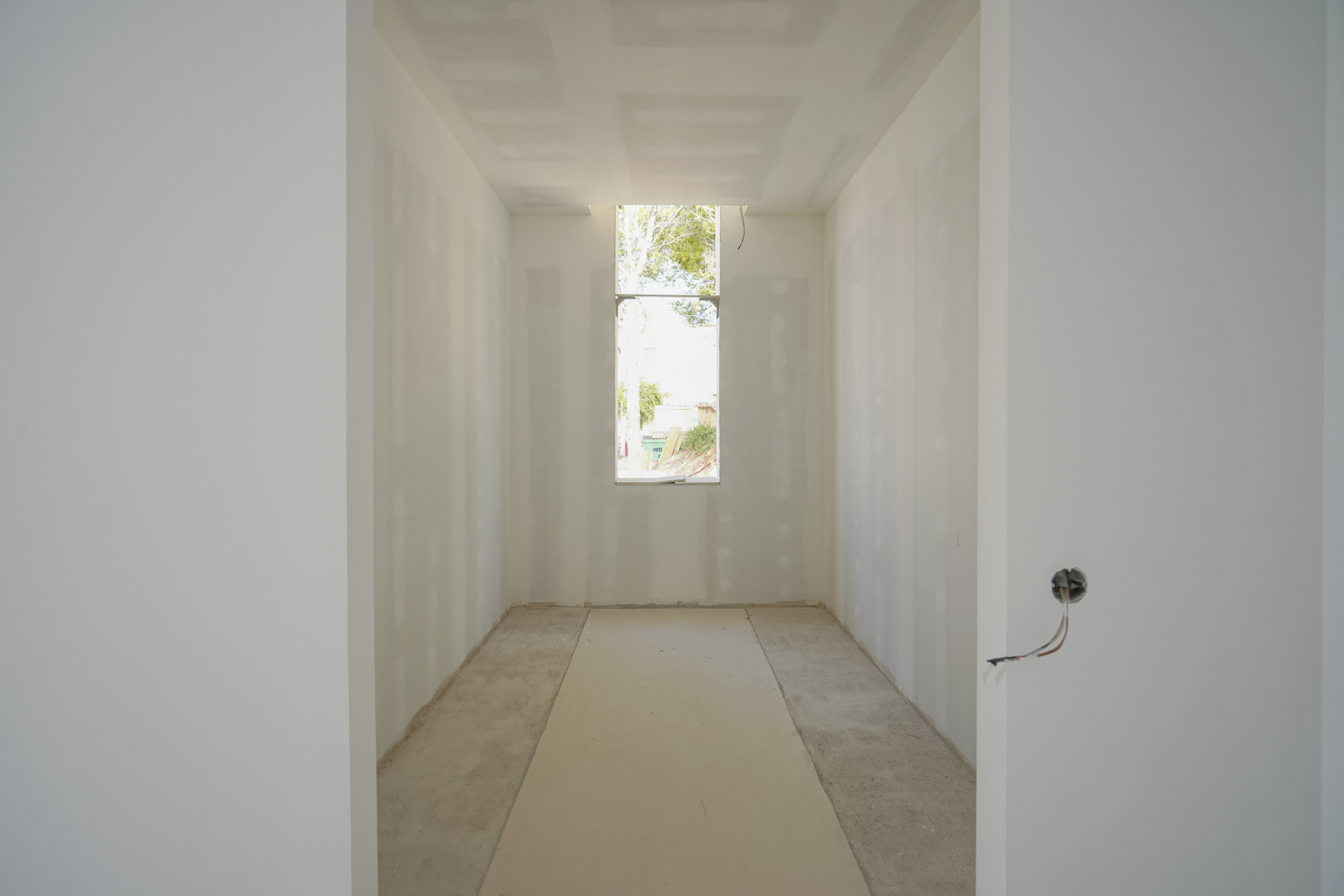 Interior view of the walk-in closet under construction, featuring a vertical window for natural light and unfinished drywall surfaces.