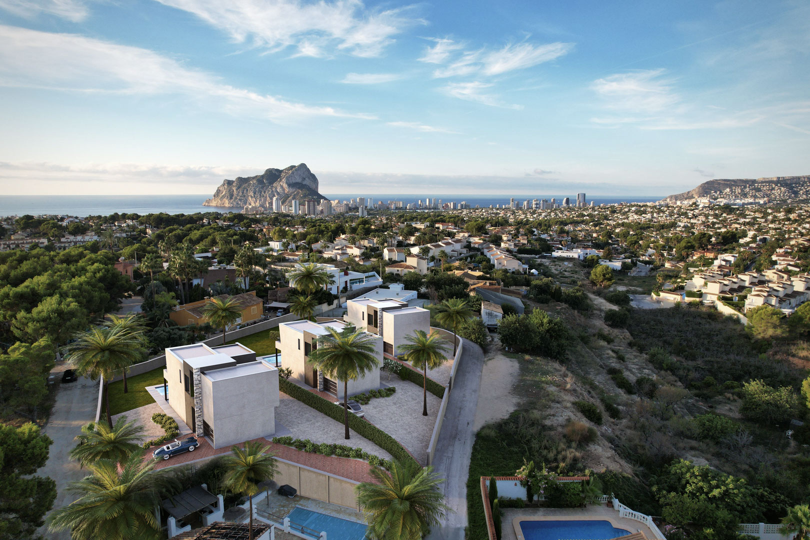 Aerial perspective of three modern cubic villas featuring private pools and expansive views toward the Peñón de Ifach and Calpe's Mediterranean skyline.