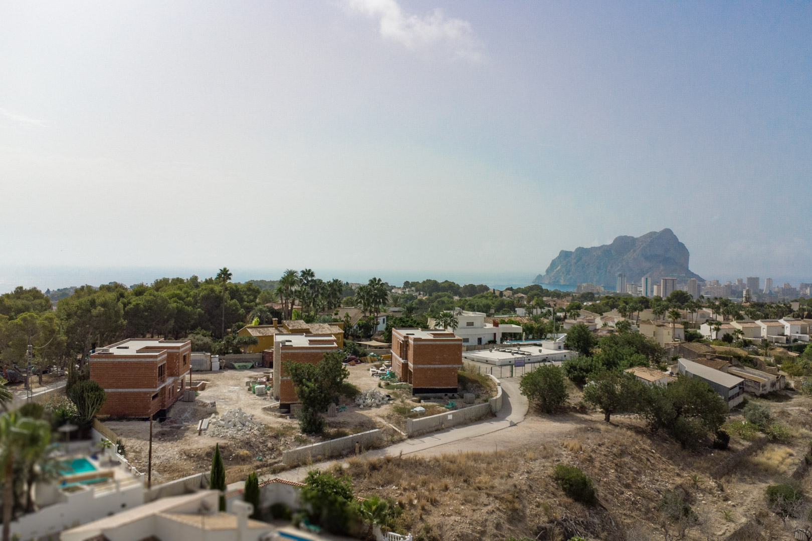 Elevated view of the three villas under construction in Partida Gran Sol, featuring the Peñón de Ifach and Calpe skyline against the Mediterranean Sea.