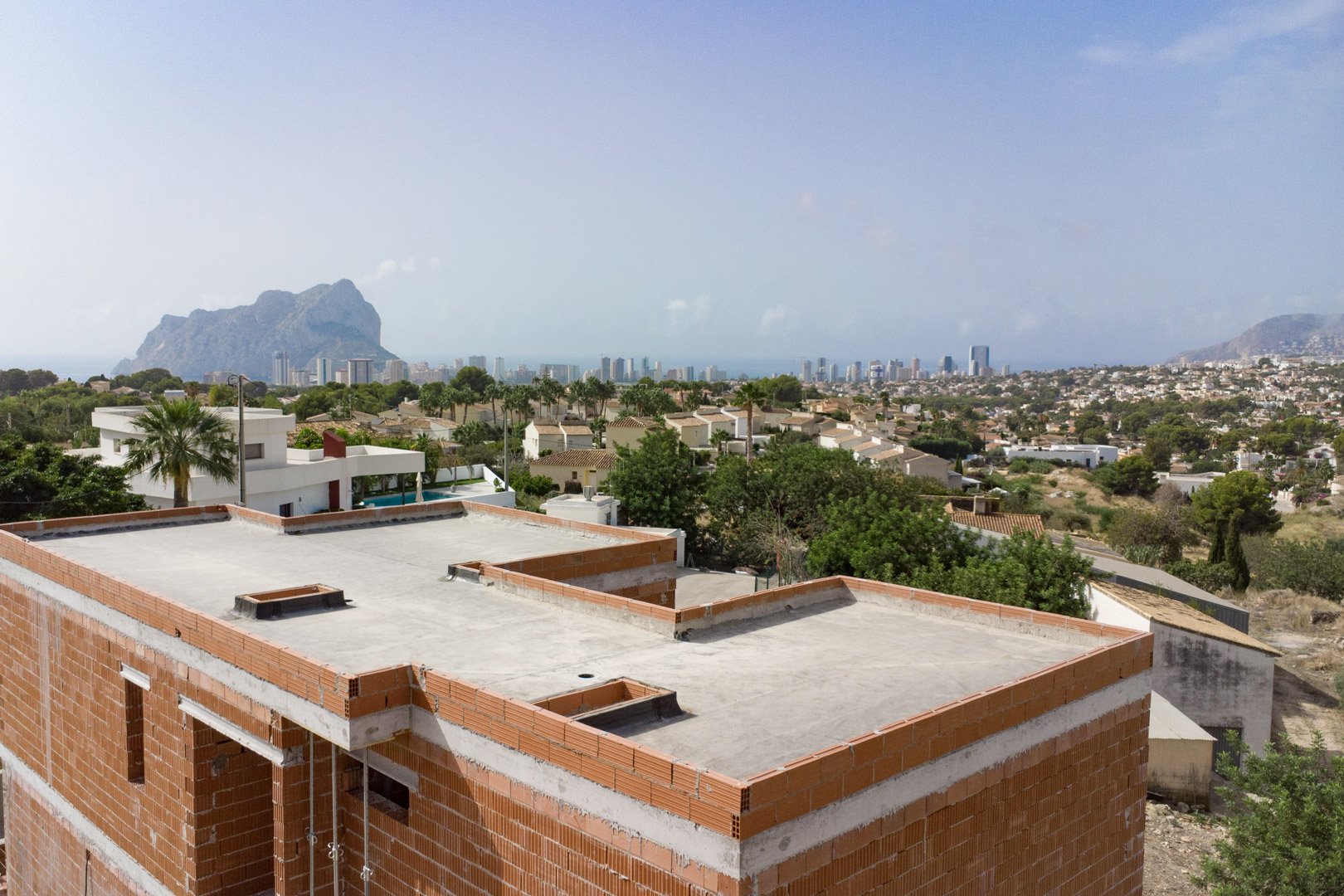 Panoramic view from the brick structure under construction, overlooking the Calpe skyline and the iconic Peñón de Ifach rock formation.
