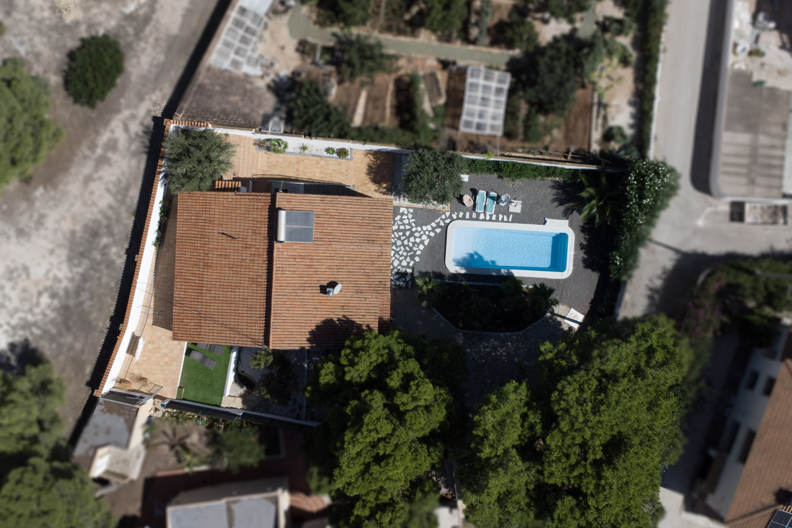 Aerial top-down view of the villa showcasing the plot layout, rectangular swimming pool, terracotta terraces, and rooftop solar panel system.