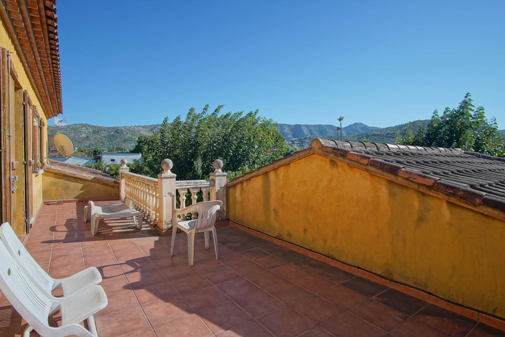 Upper terrace featuring rustic terracotta tiling and a stone balustrade, providing panoramic views of the Segaria mountain range and lush surroundings.