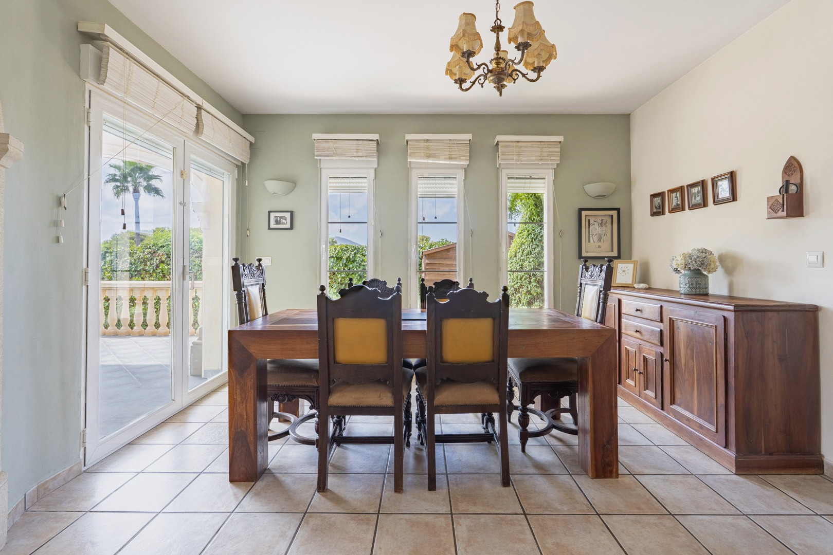 Bright dining room featuring a solid wood table, matching sideboard, and access to an outdoor terrace.