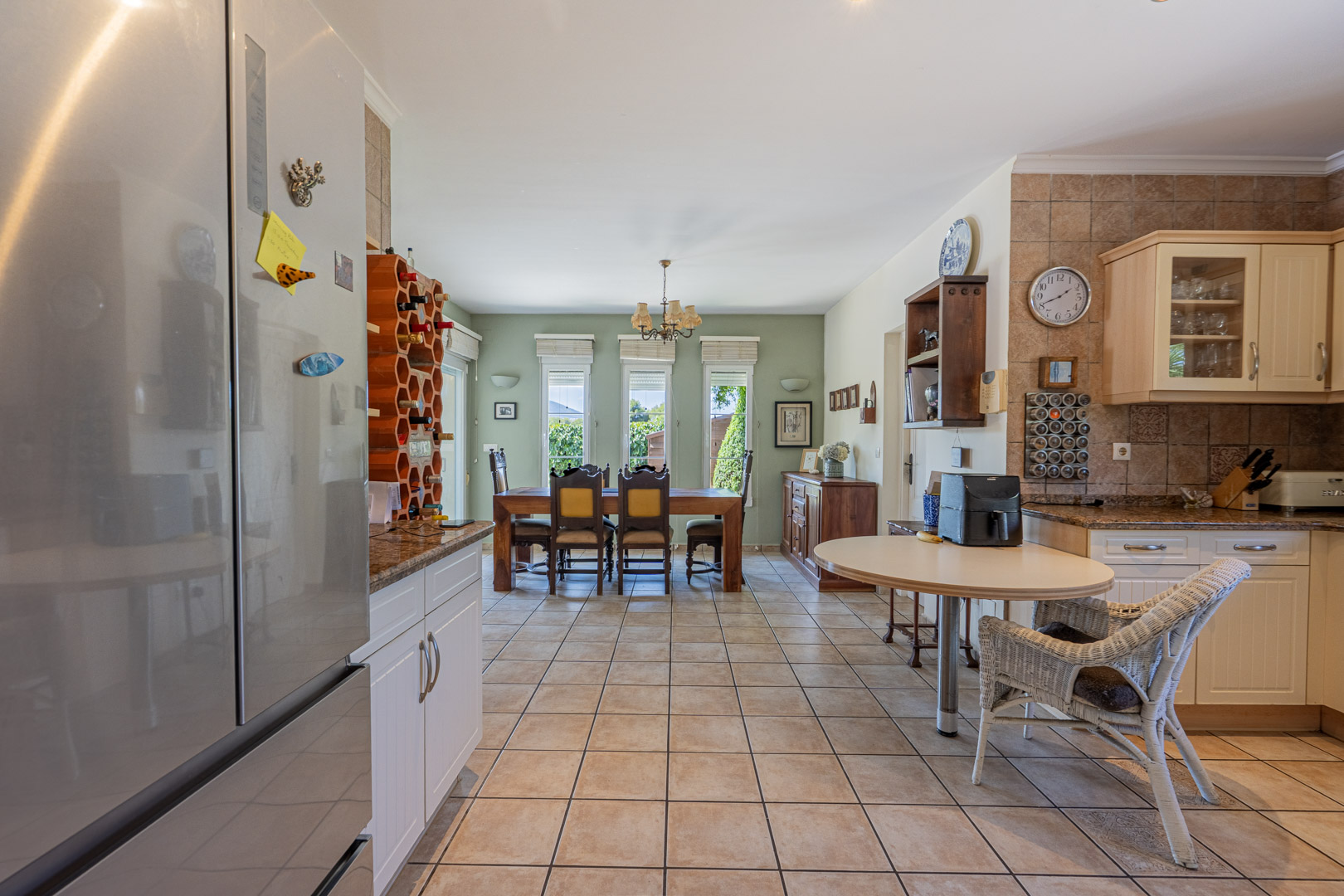 Spacious kitchen featuring a wood dining table, white cabinets, and a honeycomb-style wine rack.