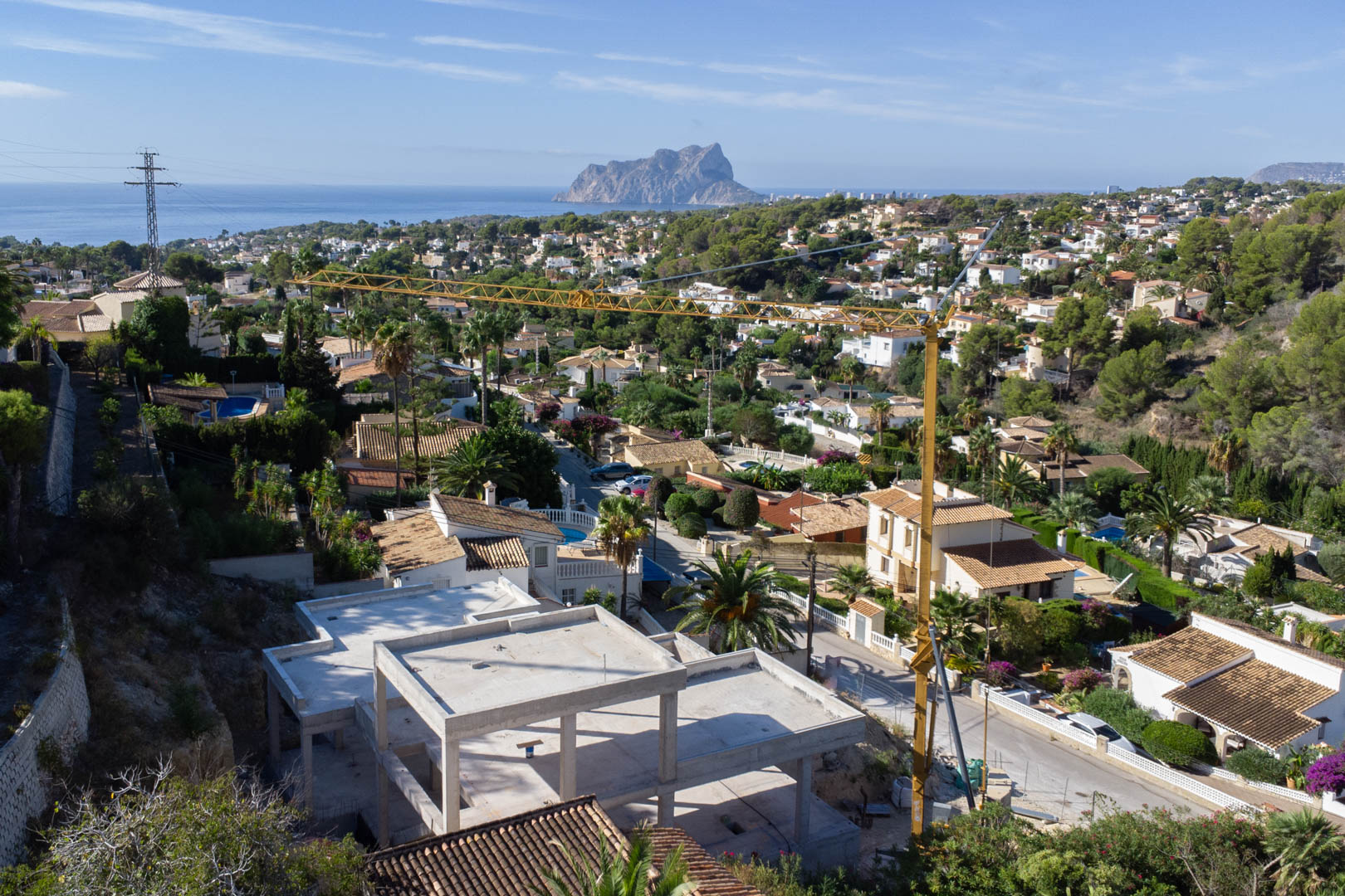Elevated view of the concrete structure under construction, showcasing panoramic vistas of the Mediterranean Sea and the iconic Peñón de Ifach.