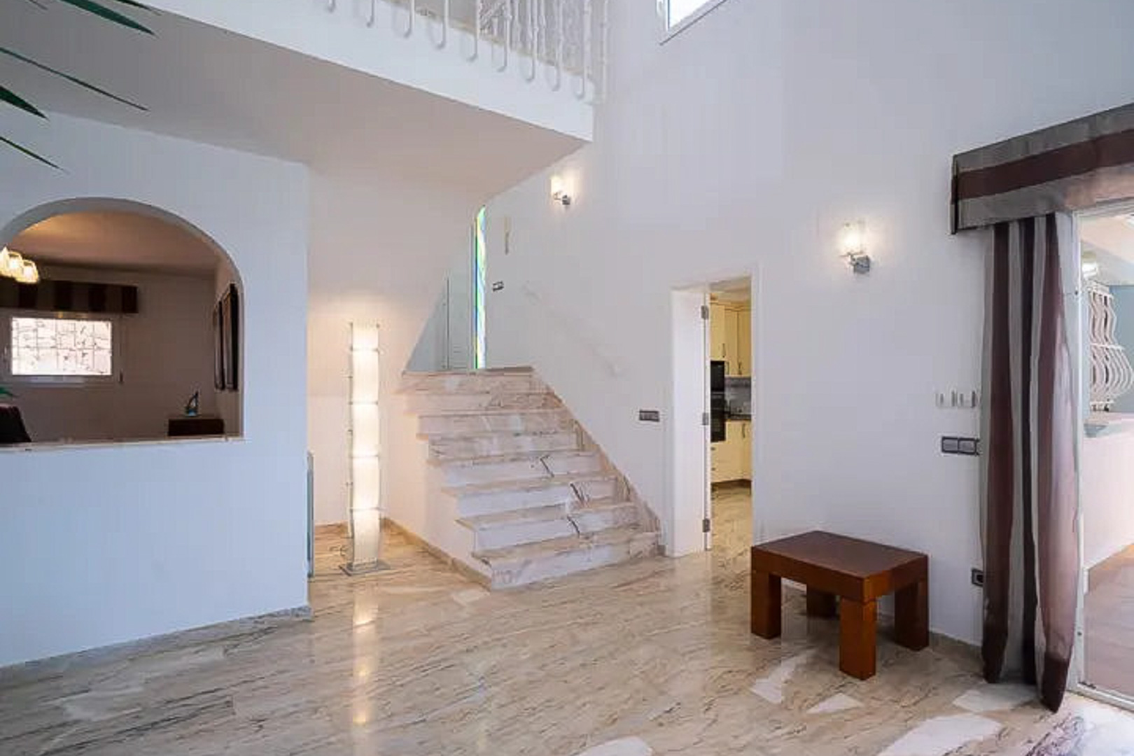 Entrance hall featuring polished marble flooring, a grand staircase, and double-height ceilings that enhance the natural light and spatial flow.