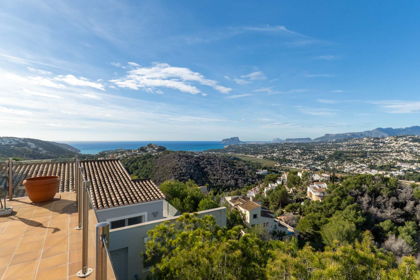 Tiled terrace with stainless steel railings featuring expansive views of the Mediterranean Sea, the Peñón de Ifach, and the coastal mountains of Moraira.