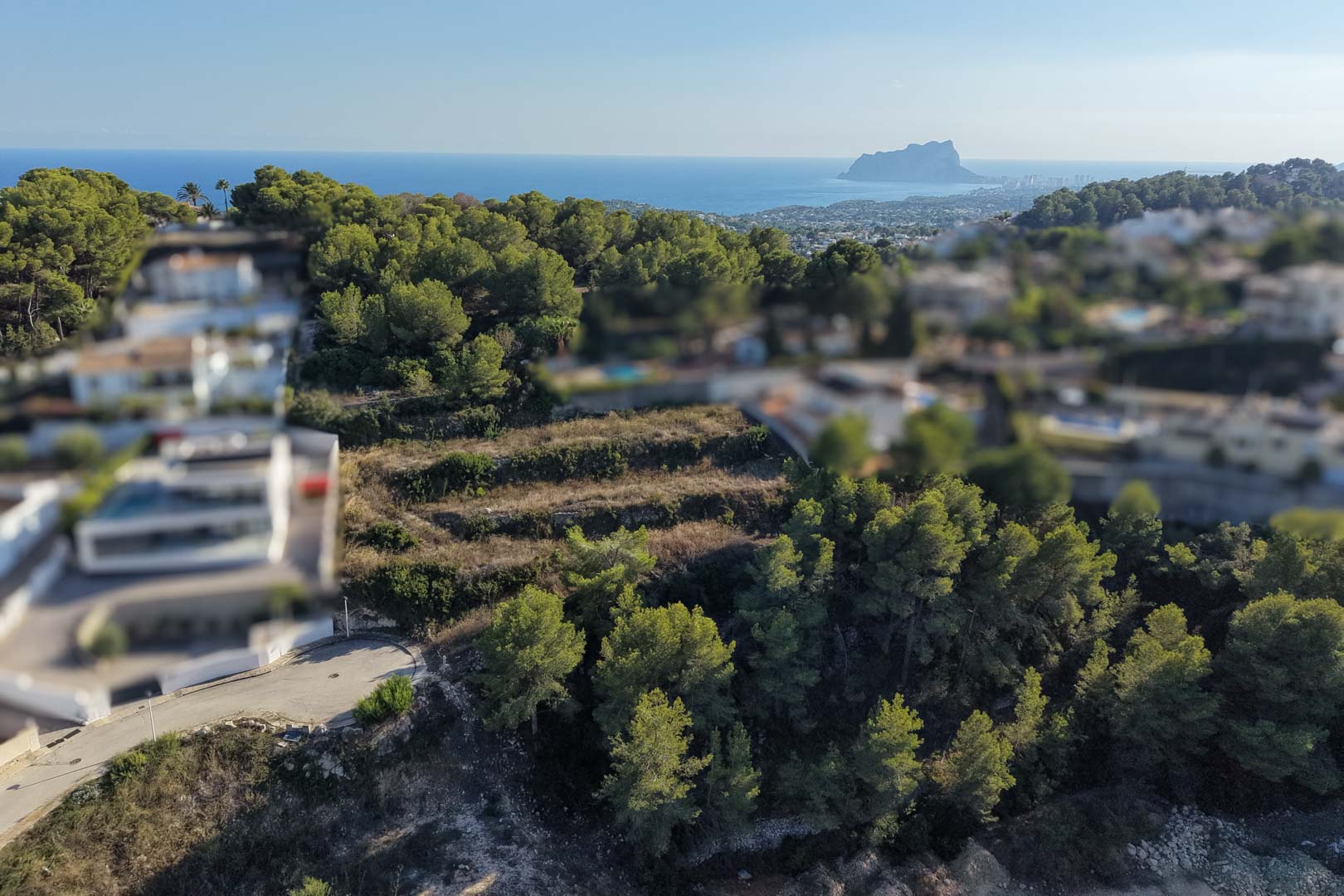 Terraced urban plot surrounded by pine trees, offering panoramic views of the Mediterranean Sea and the Peñón de Ifach on the horizon.