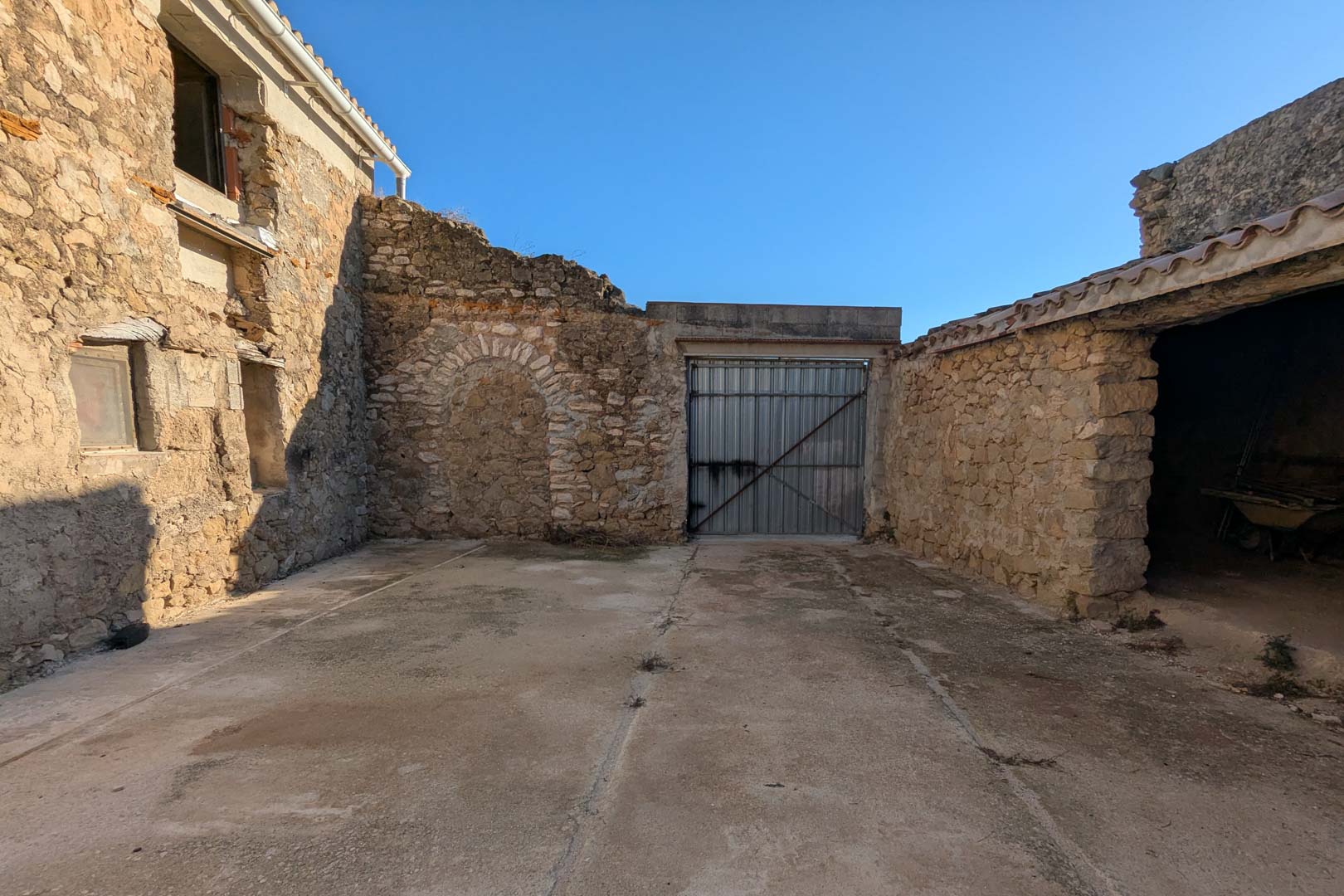 Exterior courtyard with traditional stone masonry, a bricked-up archway, and direct access to the original agricultural stables.