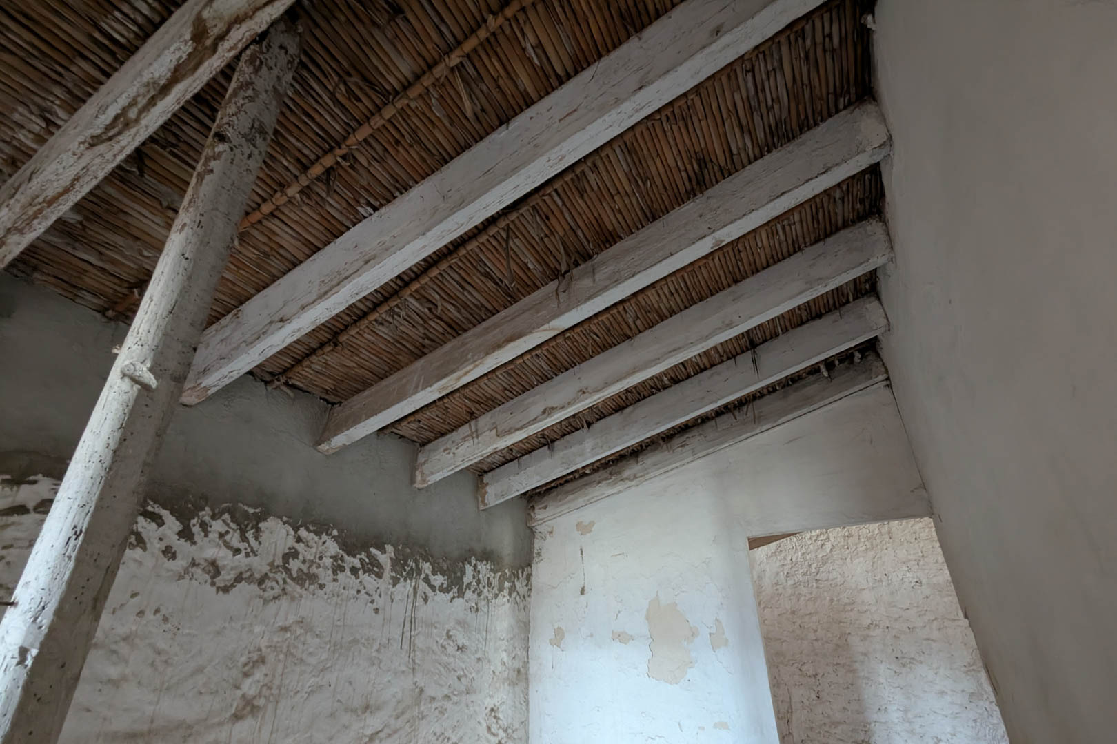 Interior view showcasing the original cane ceiling and lime-washed wooden beams. The natural stone walls retain their traditional lime coating.