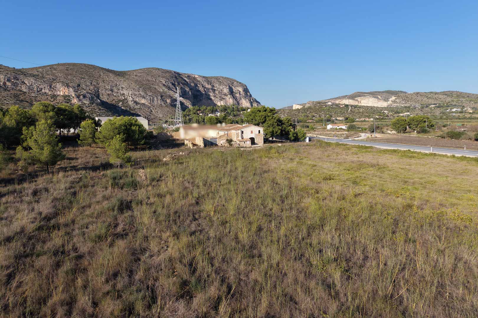 Panoramic view of the traditional stone house set on a vast rural plot, surrounded by Mediterranean vegetation and mountain scenery in Teulada.