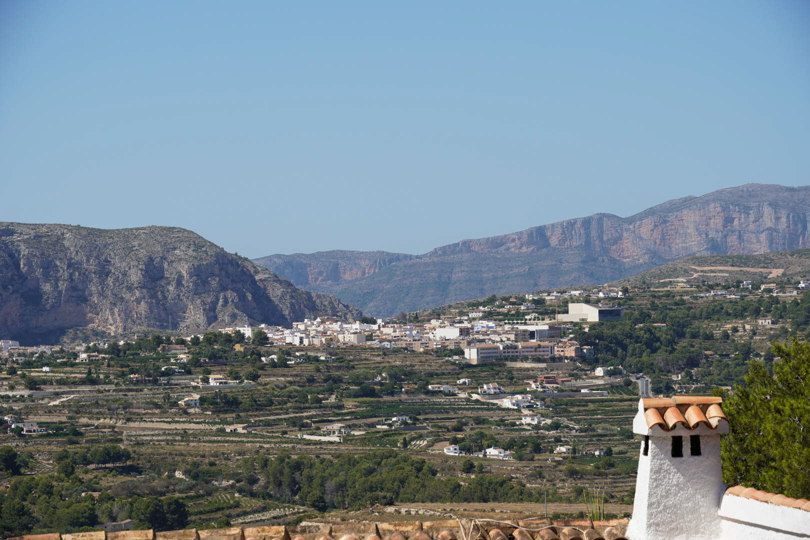 Panoramic views from the property overlooking the town of Teulada, featuring traditional agricultural terraces and rugged mountain ranges under a clear sky.
