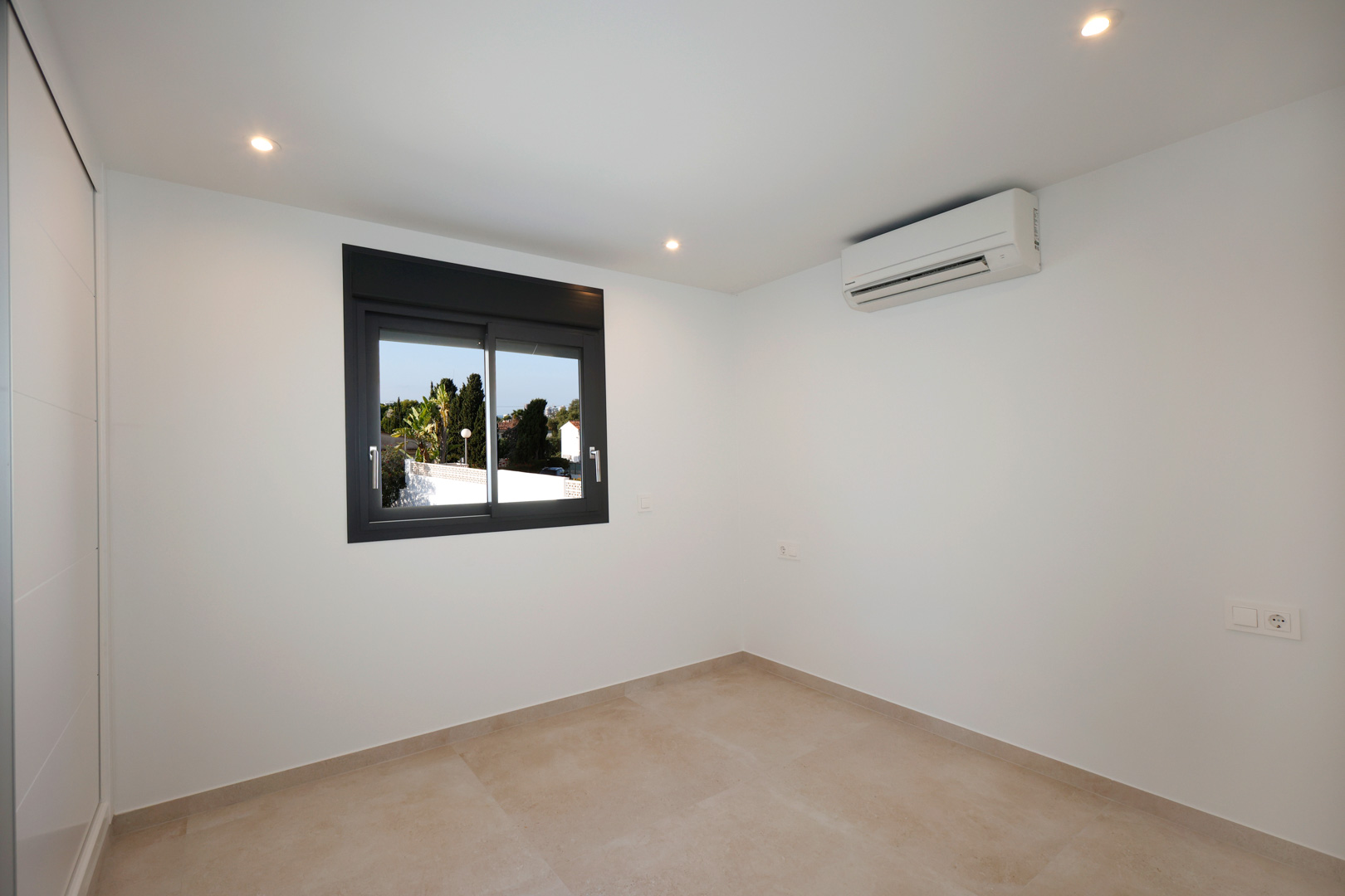 Bright bedroom featuring porcelain stoneware flooring, recessed LED lighting, split air conditioning, and a Technal aluminum window.