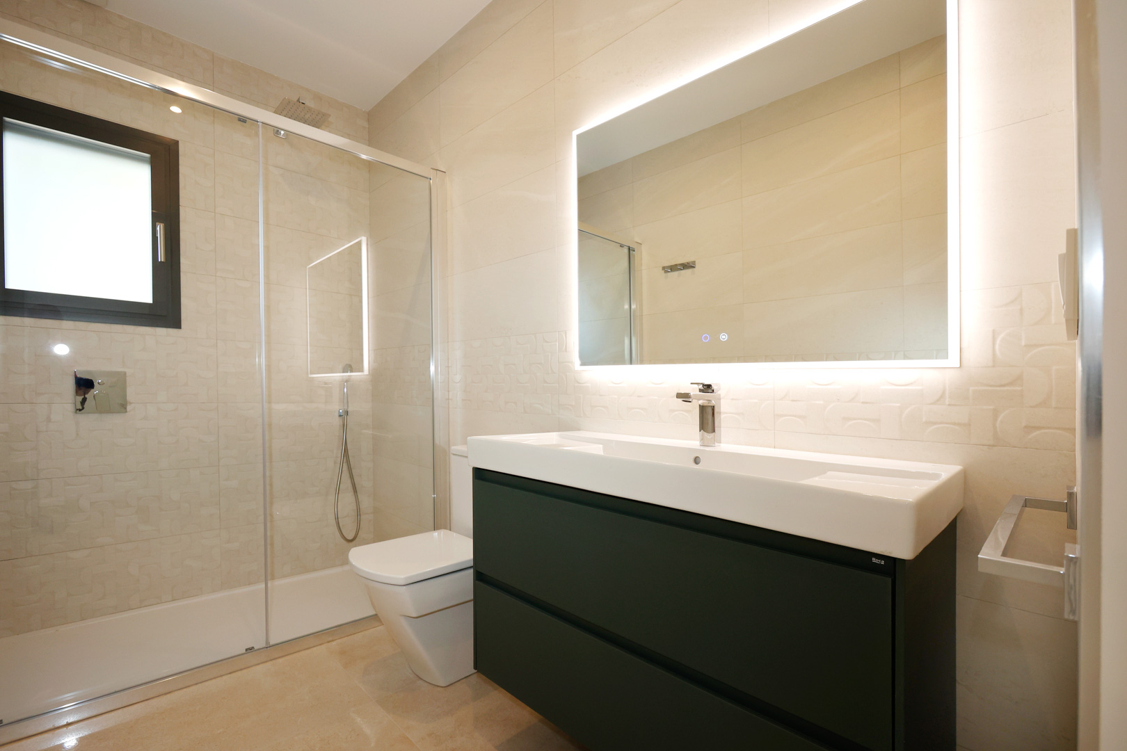 Contemporary bathroom with an anthracite floating vanity, Roca sink, and LED-backlit mirror. Features a walk-in shower with a glass screen and textured porcelain wall tiles.