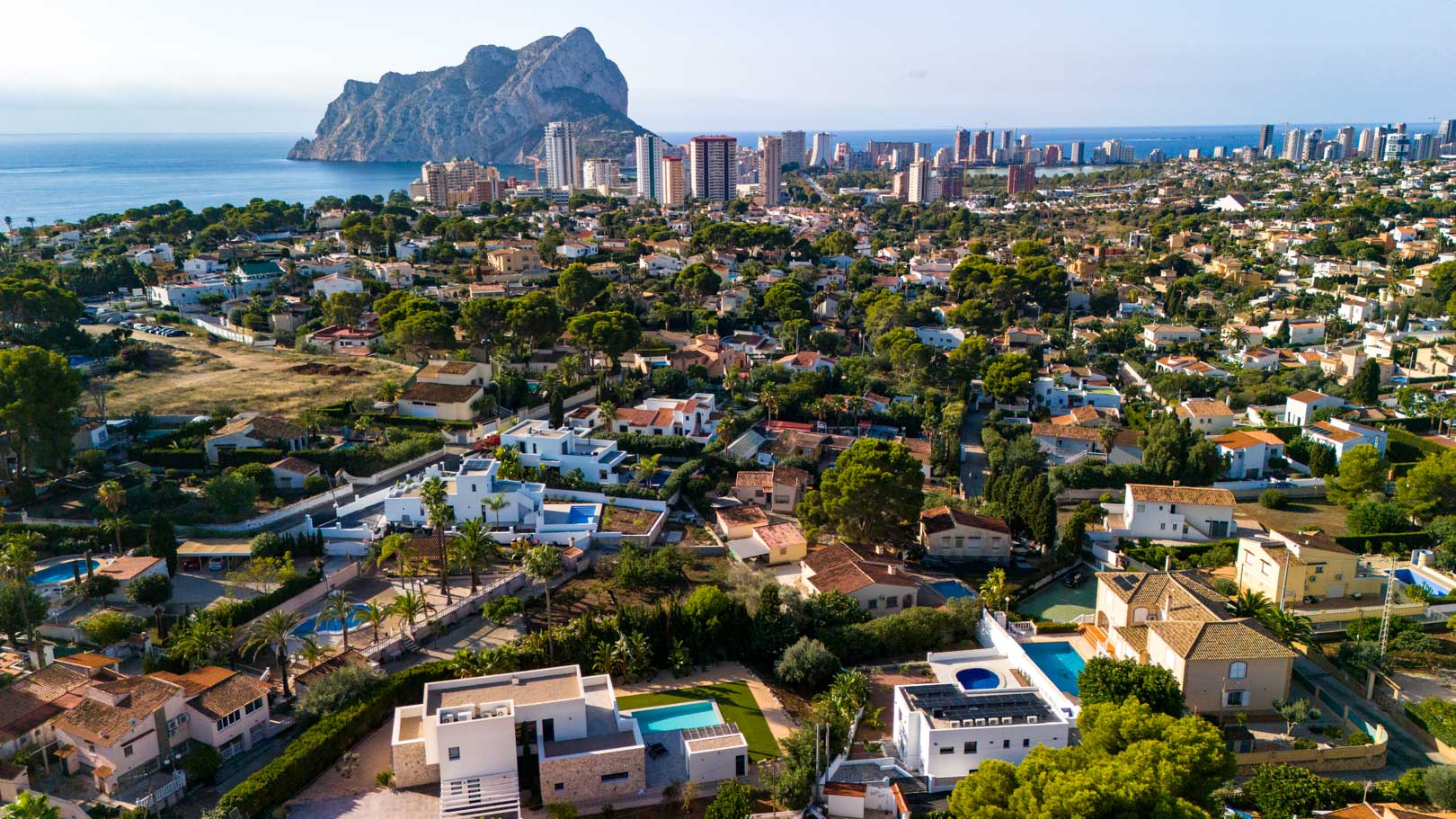 Panoramic aerial view of the villa in Calpe, featuring its rooftop solar installation and clear views of the Peñón de Ifach and the Mediterranean Sea.