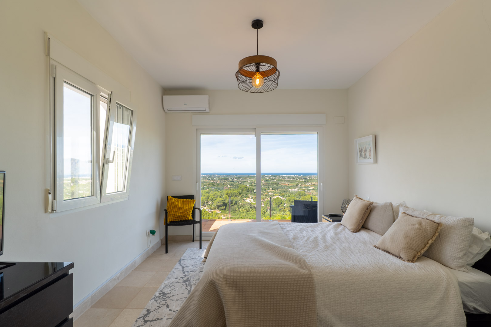 Bedroom with terrace access and panoramic sea views. Features include air conditioning, tiled flooring, and a large sliding glass door for abundant natural light.