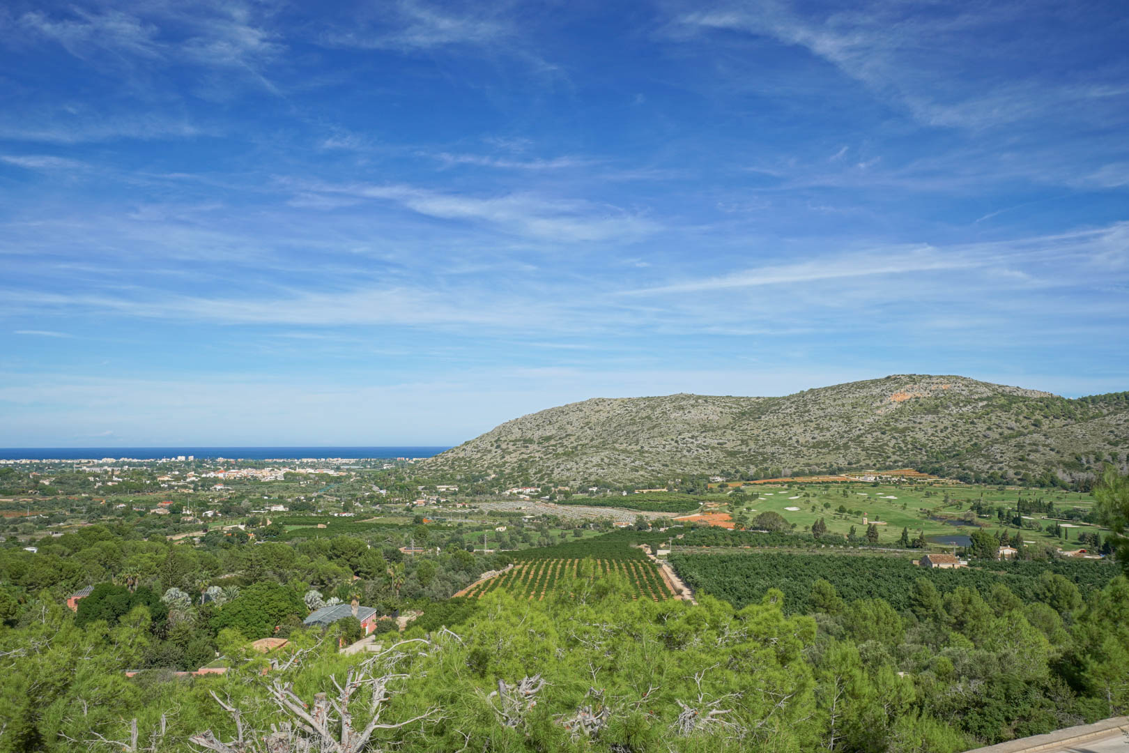 Panoramic views from the property overlooking La Sella golf course, the lush agricultural valley, and the Mediterranean Sea horizon under a clear sky.
