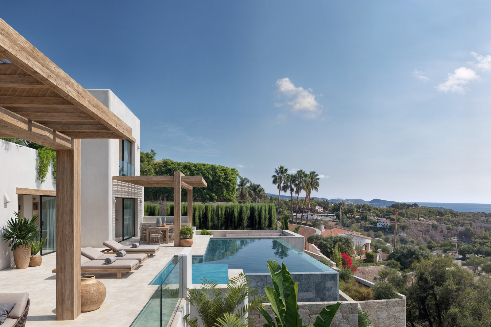 Outdoor terrace featuring an infinity pool, wooden pergolas, and panoramic sea views. The white Ibicenco-style facade blends with the surrounding Mediterranean vegetation.