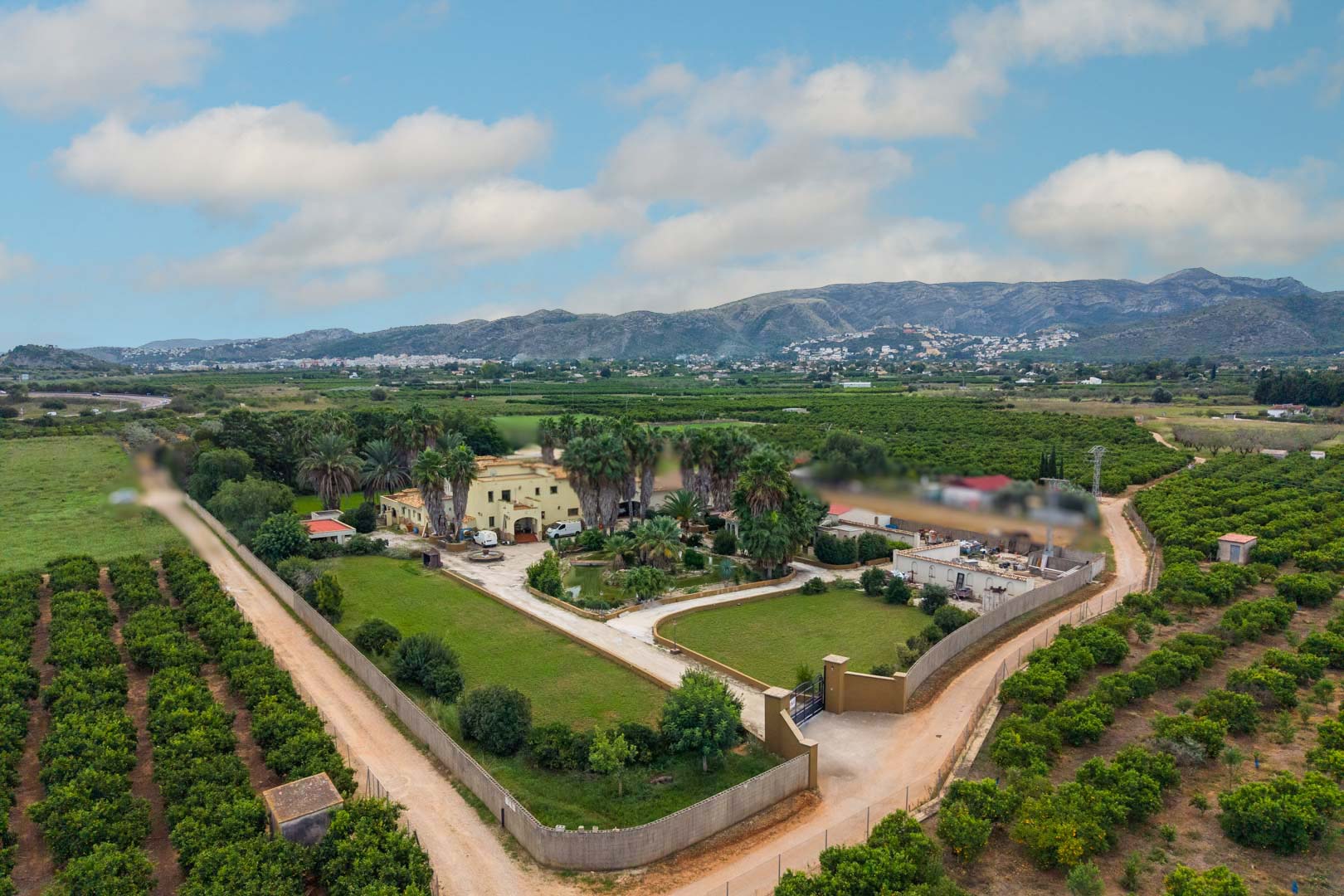 Aerial perspective of the 10,000 m² estate showcasing the main residence, central pond, and landscaped gardens surrounded by citrus groves and mountain scenery.