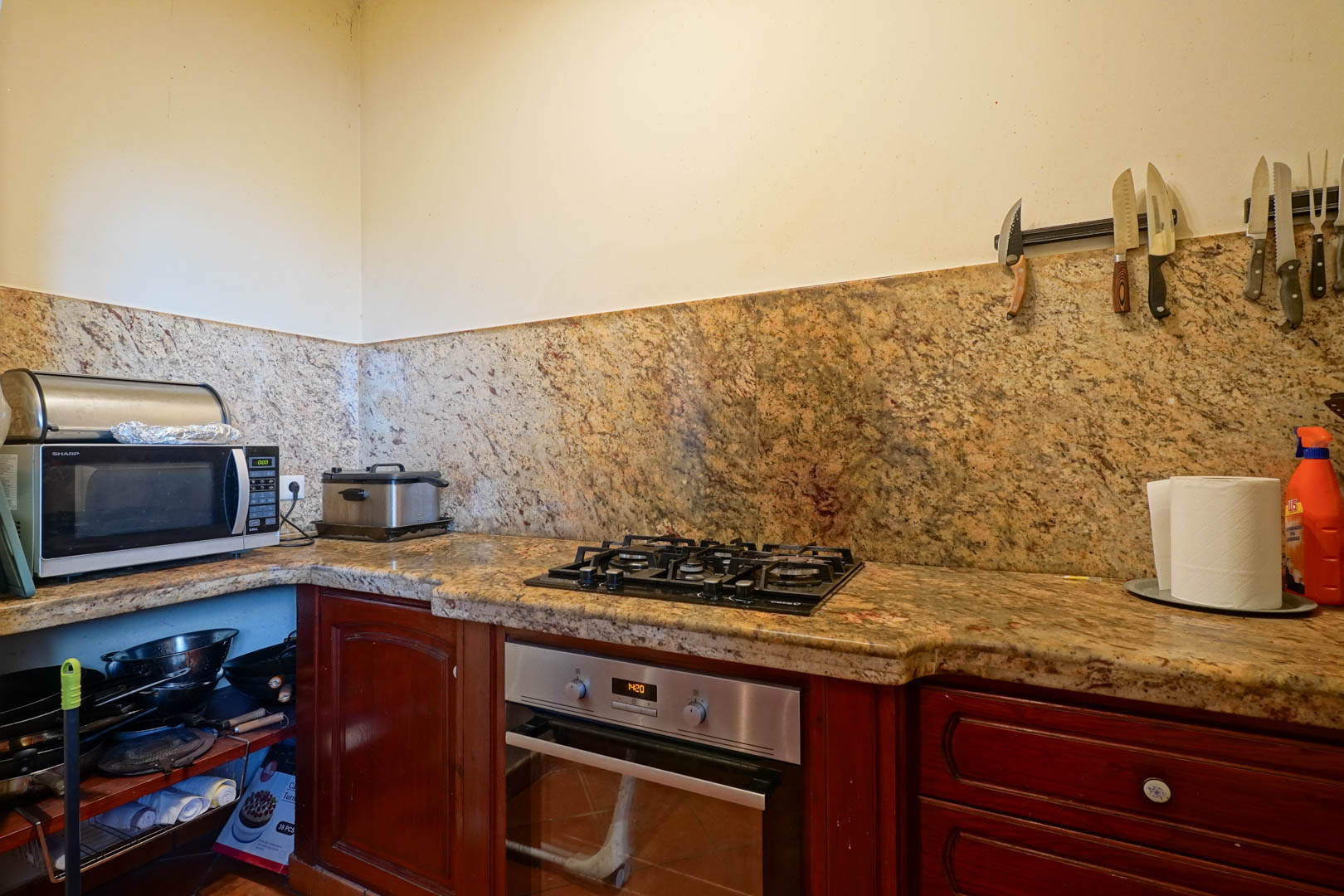 Kitchen featuring a granite countertop and matching backsplash, equipped with a gas stove, stainless steel oven, and traditional dark wood cabinetry.