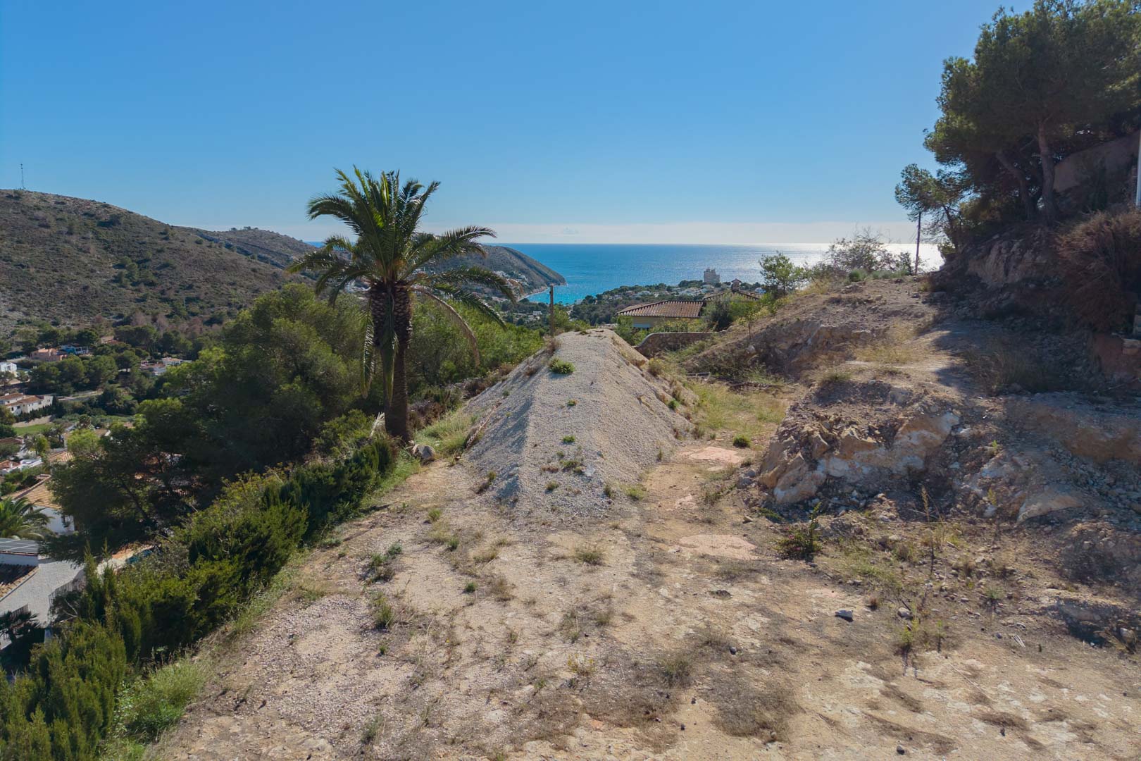 Panoramic view from the elevated plot overlooking El Portet bay, highlighting the natural Mediterranean landscape and expansive sea views in Moraira.