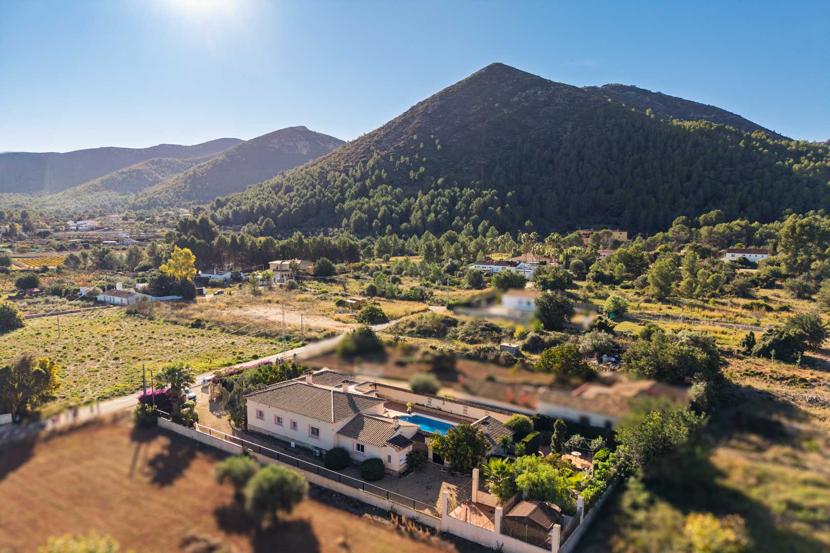 Aerial perspective of the Mediterranean villa in Jalón, featuring a central pool area and scenic views of the pine-covered mountains.