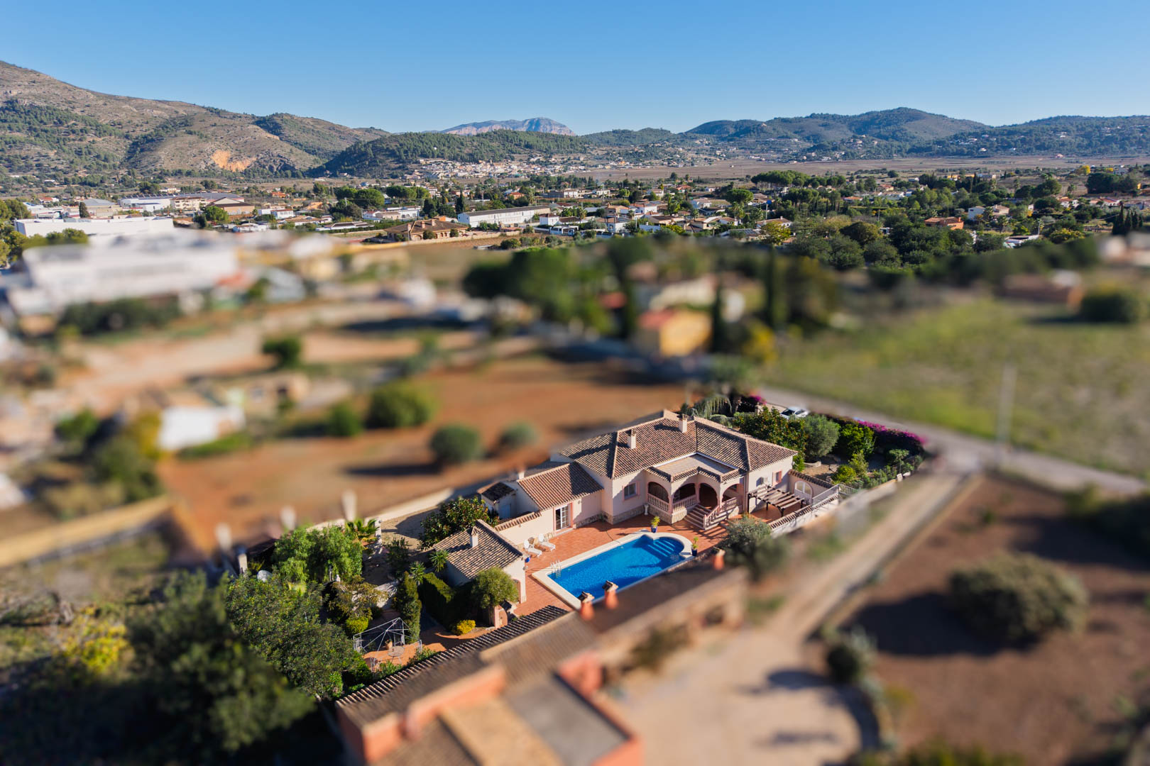 Aerial perspective of the Mediterranean villa in Jalón, showcasing the private pool, terracotta terrace, and flat plot integrated into the scenic mountain valley landscape.