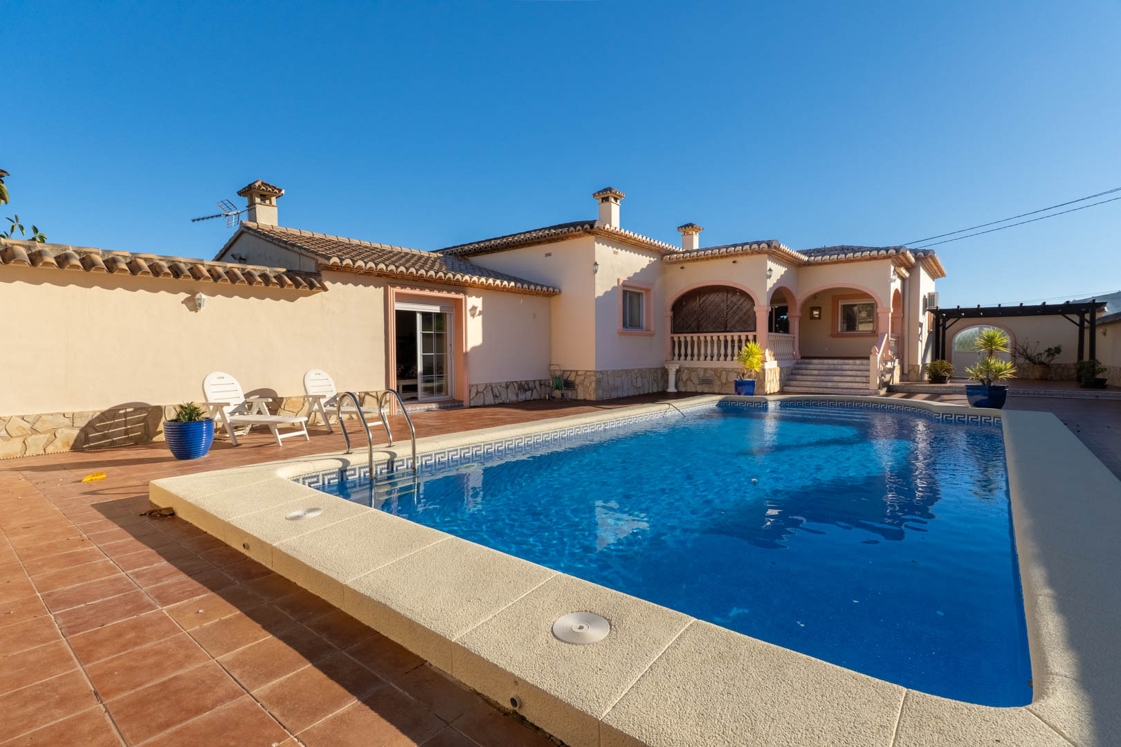 Spacious outdoor area featuring a private swimming pool, terracotta sun terrace, and a traditional Mediterranean porch with arched details.