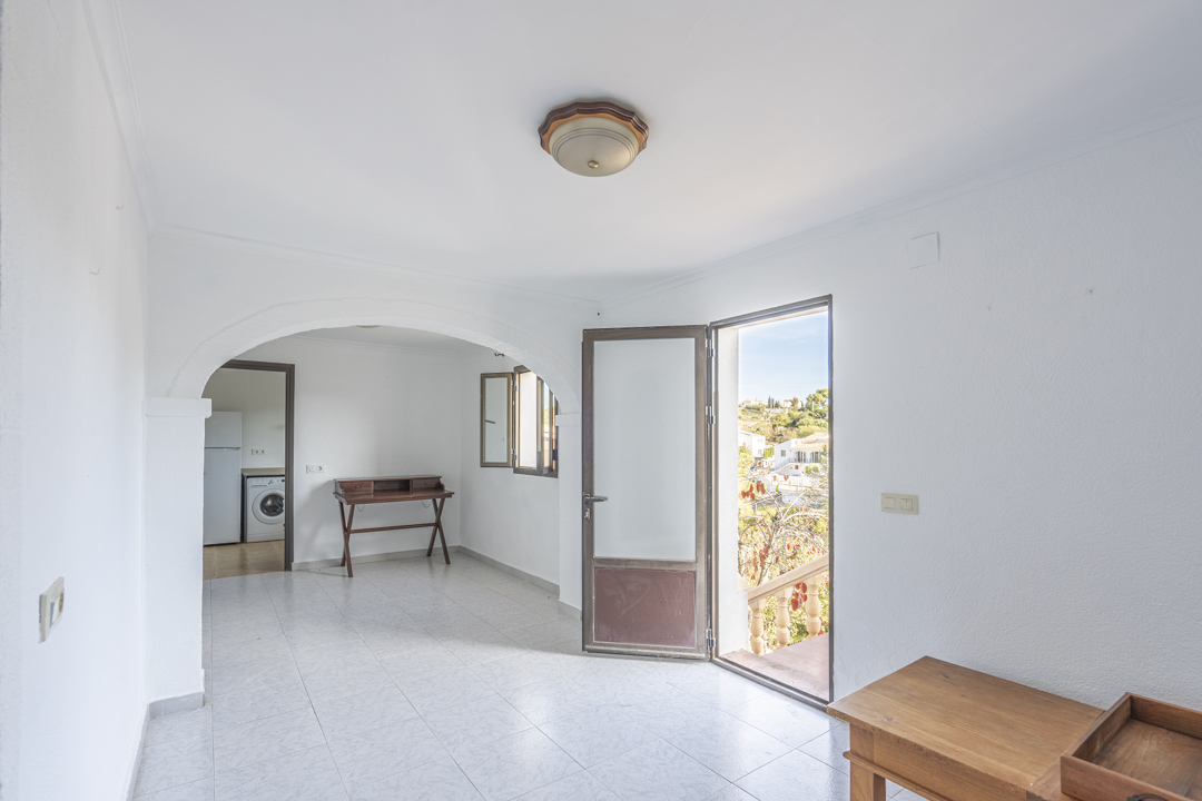 Bright living area featuring ceramic tile flooring, a decorative archway, and direct access to an outdoor terrace with views of the landscape.