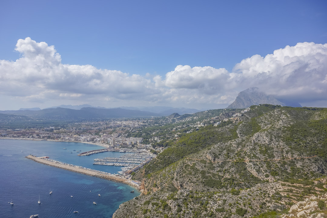 Panoramic view of Jávea bay, featuring the marina, the Mediterranean coastline, and the Montgó mountain in the background.