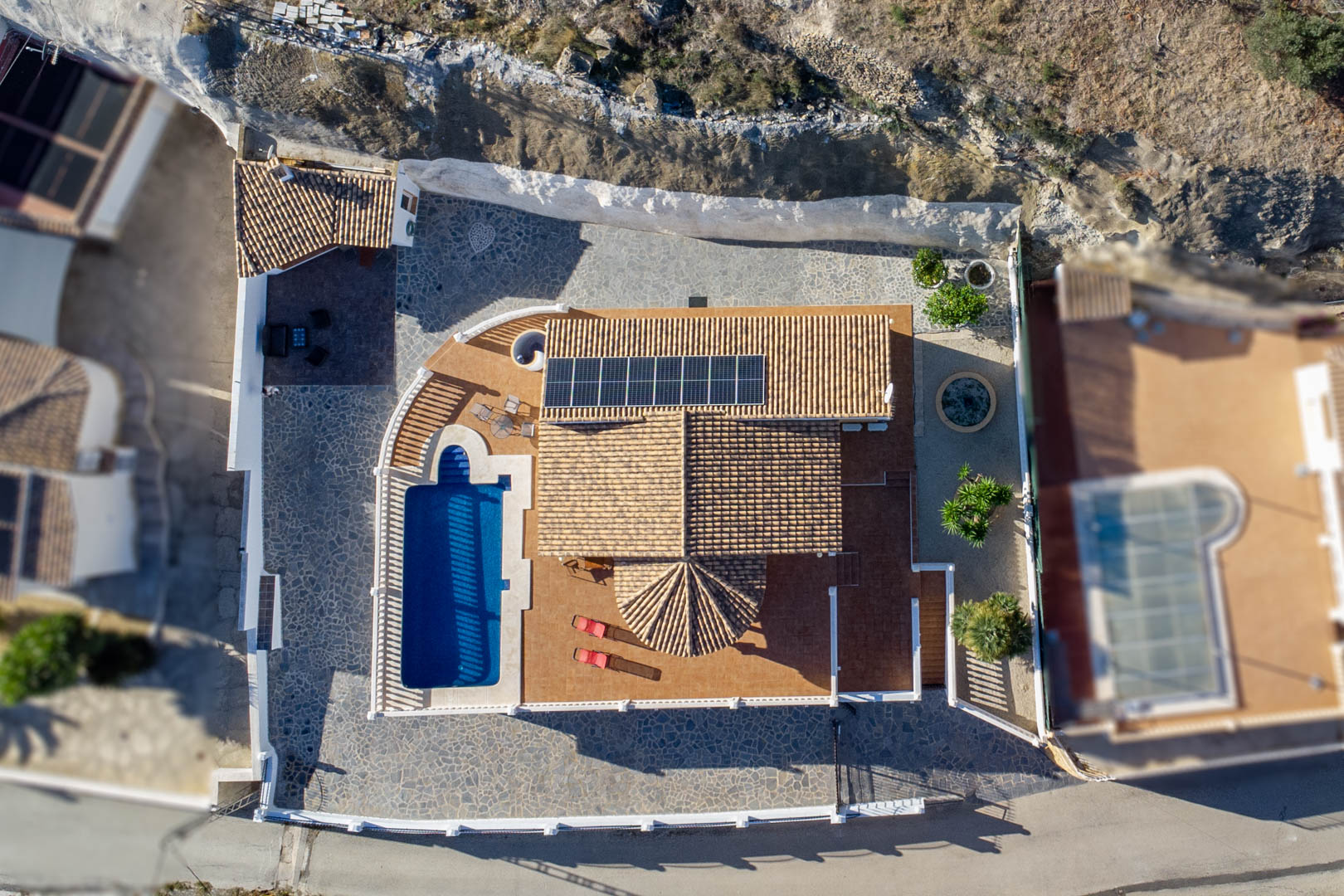 Aerial top-down perspective showing the traditional tiled roof with solar panels, the private pool, and the stone-paved outdoor living spaces.