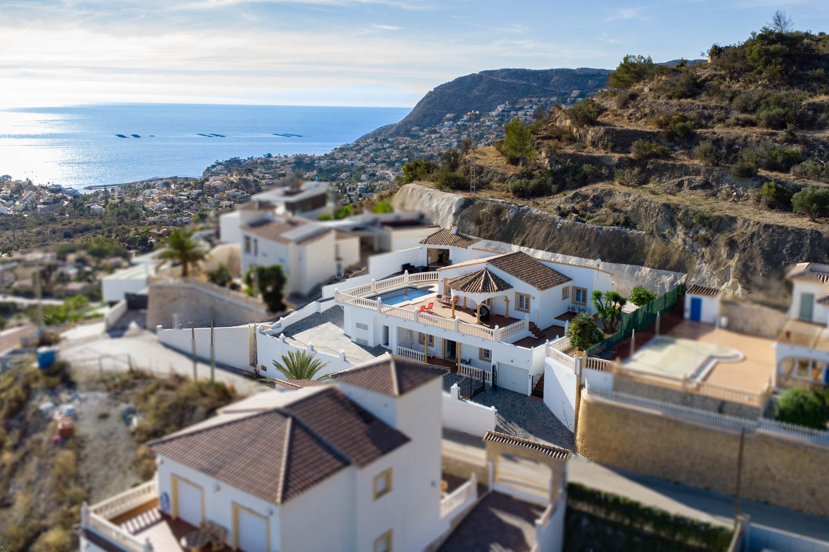Aerial view of the villa in Partida Cucarres, featuring the pool terrace, traditional terracotta roofing, and panoramic views of the Mediterranean coast.