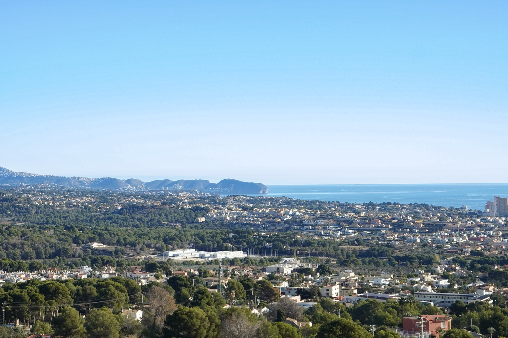 Elevated panoramic view of the Mediterranean coastline and Cap d’Or, overlooking the residential areas and dense pine forests of Calpe.