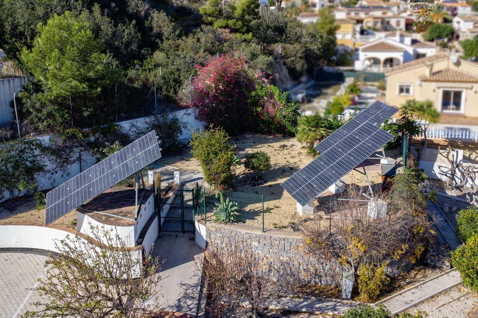 Aerial view of the advanced photovoltaic system featuring three motorized solar towers installed within the property's landscaped grounds and stone walls.