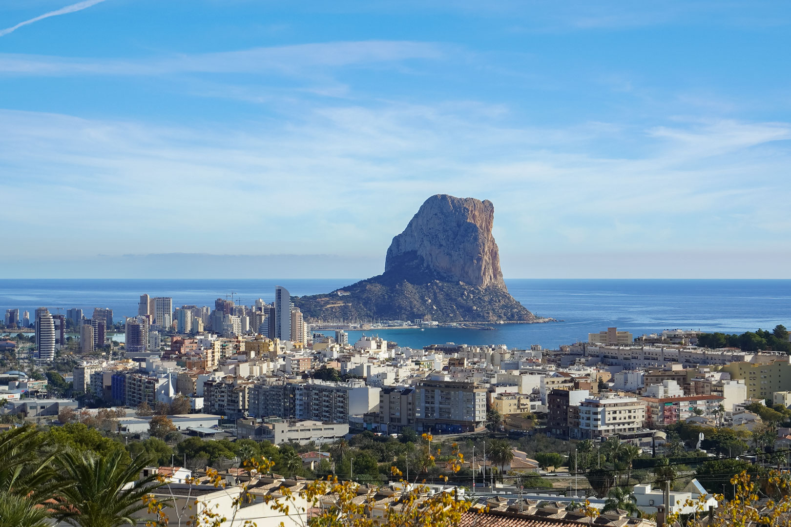 Elevated panoramic view of the Peñón de Ifach and Calpe’s skyline, showcasing the Mediterranean coastline and the coastal city below.