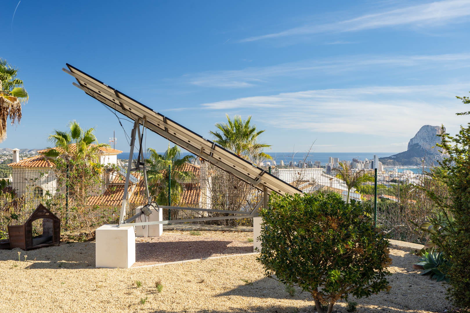 Motorized solar tracker tower on a gravel plot, offering panoramic views of the Calpe skyline and the Peñón de Ifach rock formation.