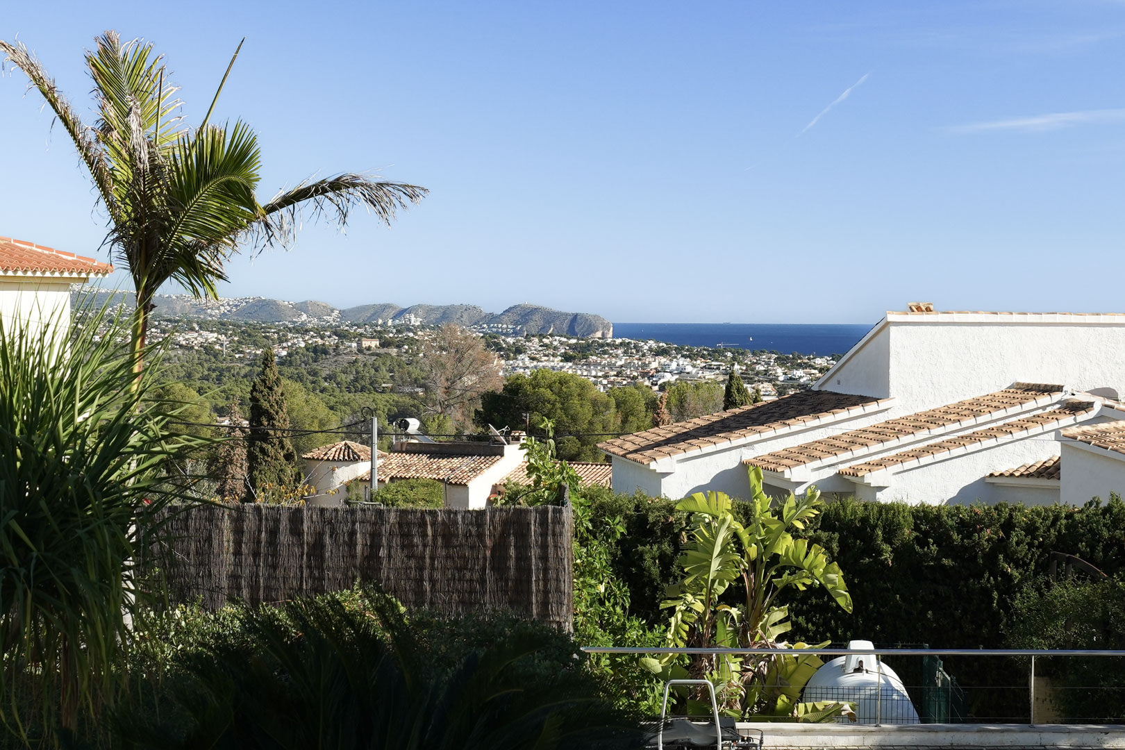 Panoramic views of the Mediterranean Sea and Cap d'Or, framed by lush tropical vegetation and traditional white-washed coastal architecture.