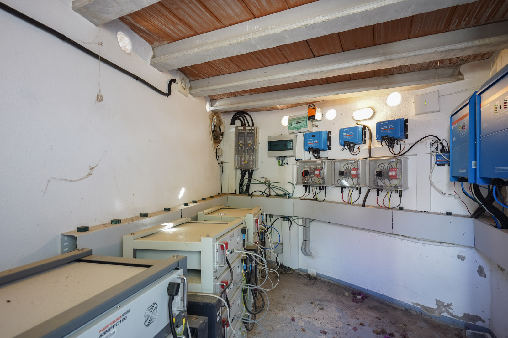 Technical room housing a 30 kW photovoltaic system with Victron Energy inverters and Narada lithium battery towers for sustainable energy storage.