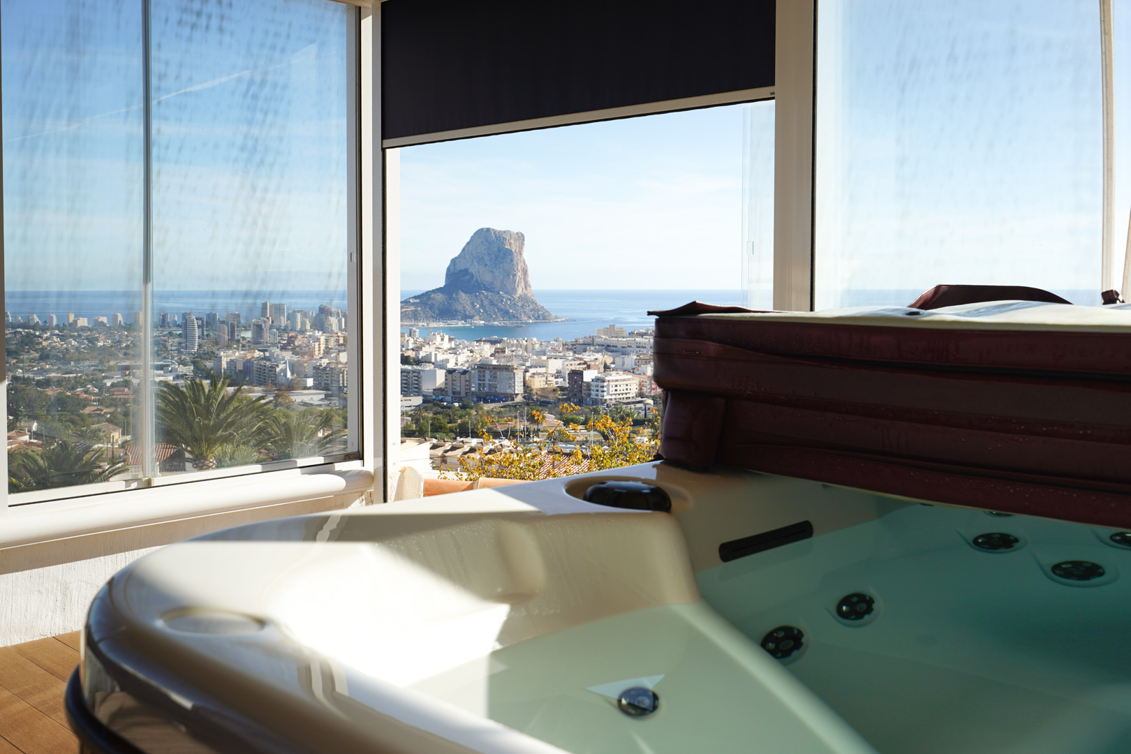 Upper-level jacuzzi area featuring a glass enclosure and panoramic views overlooking the Peñón de Ifach, Calpe skyline, and the Mediterranean Sea.