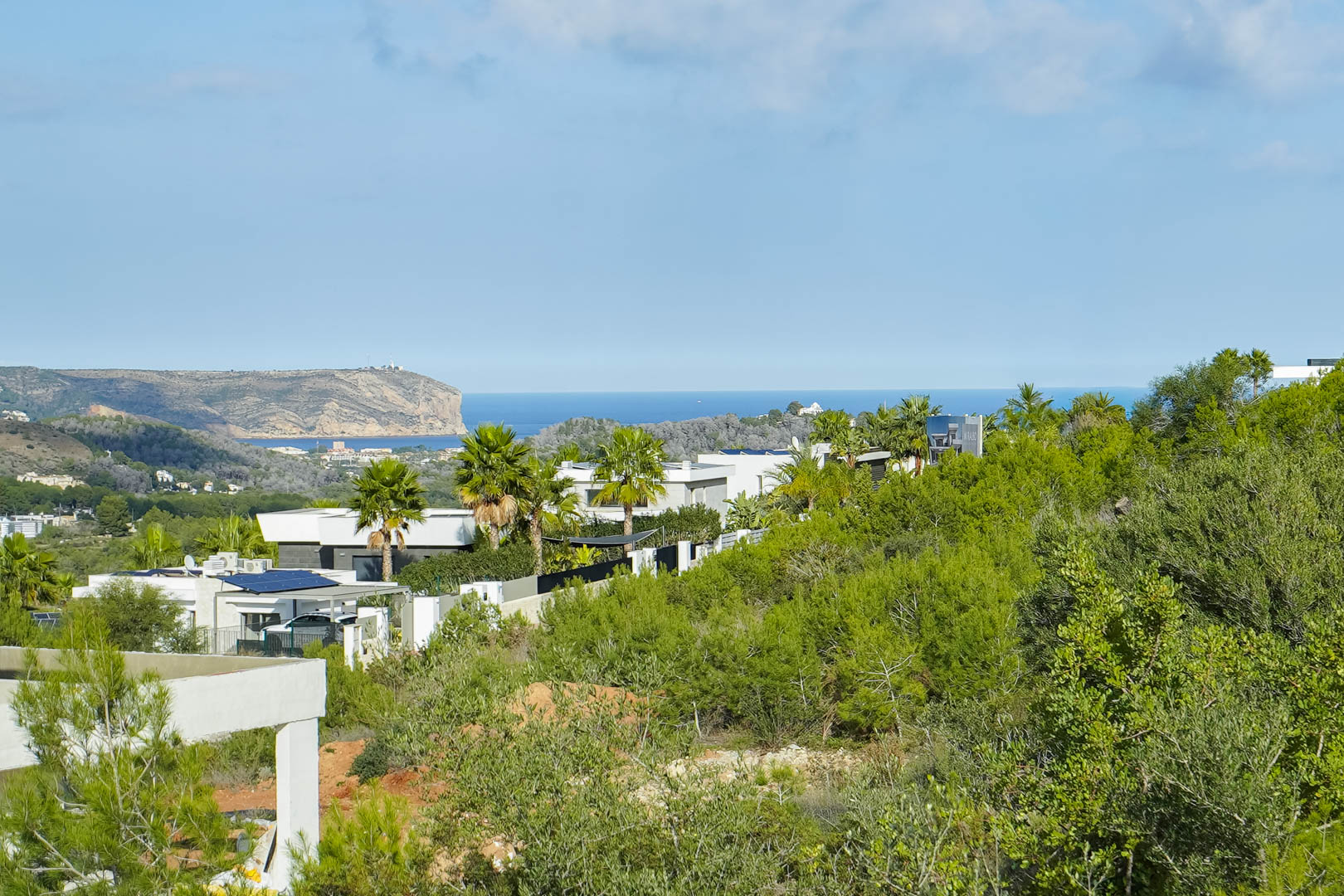 Panoramic views of the Mediterranean Sea and Cabo de San Antonio from the plot, surrounded by modern villas and lush Mediterranean greenery.