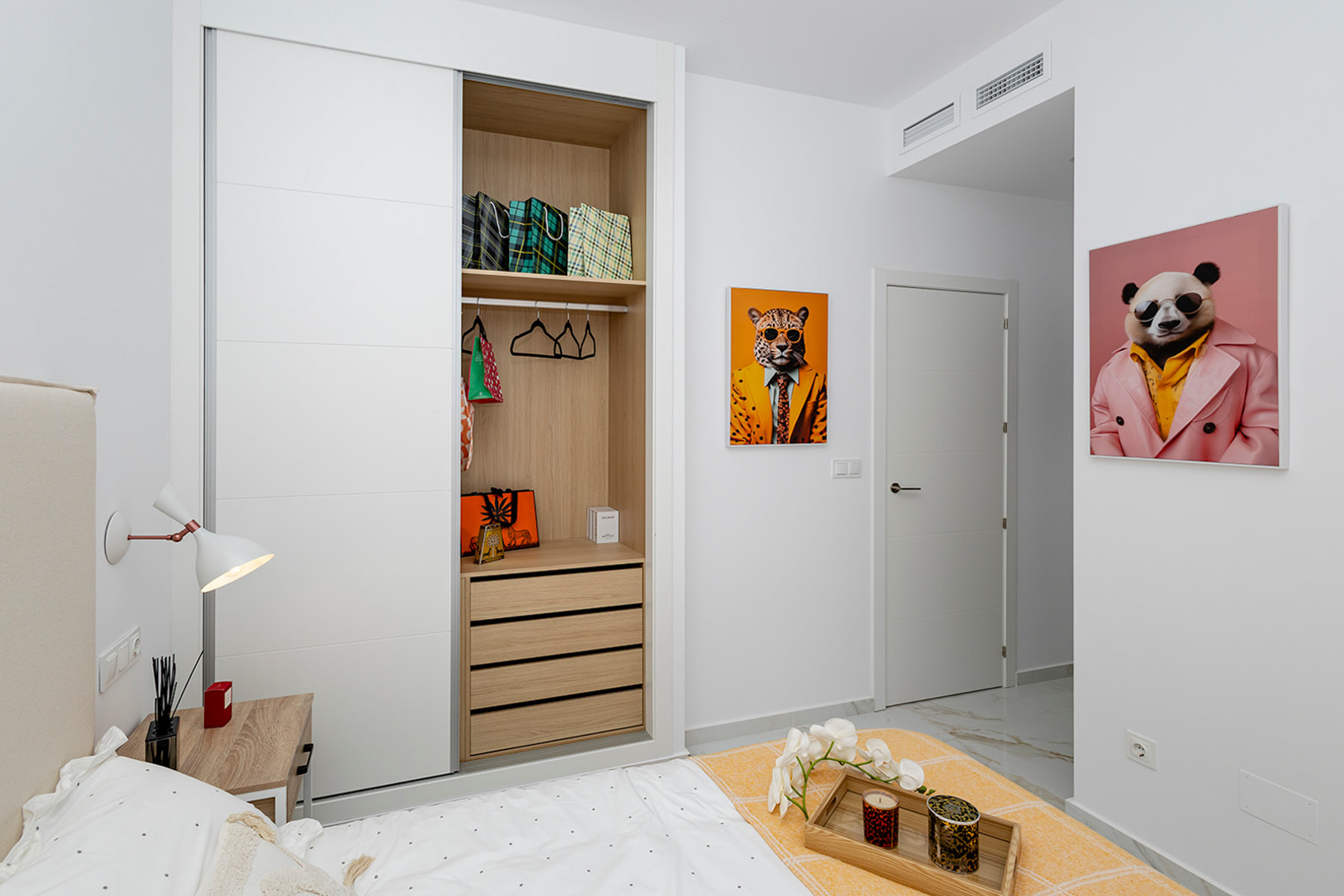 Bedroom featuring a built-in wardrobe with white sliding doors and wood-finish interior. Includes marble-effect flooring and ducted air conditioning.