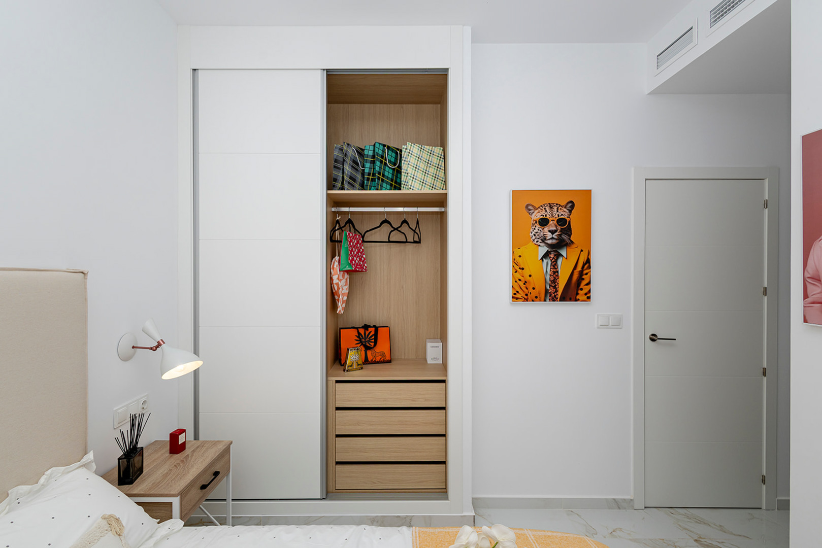 Bedroom featuring a built-in wardrobe with white sliding doors and wood-finish interior. Includes marble-effect flooring and integrated ducted air conditioning.