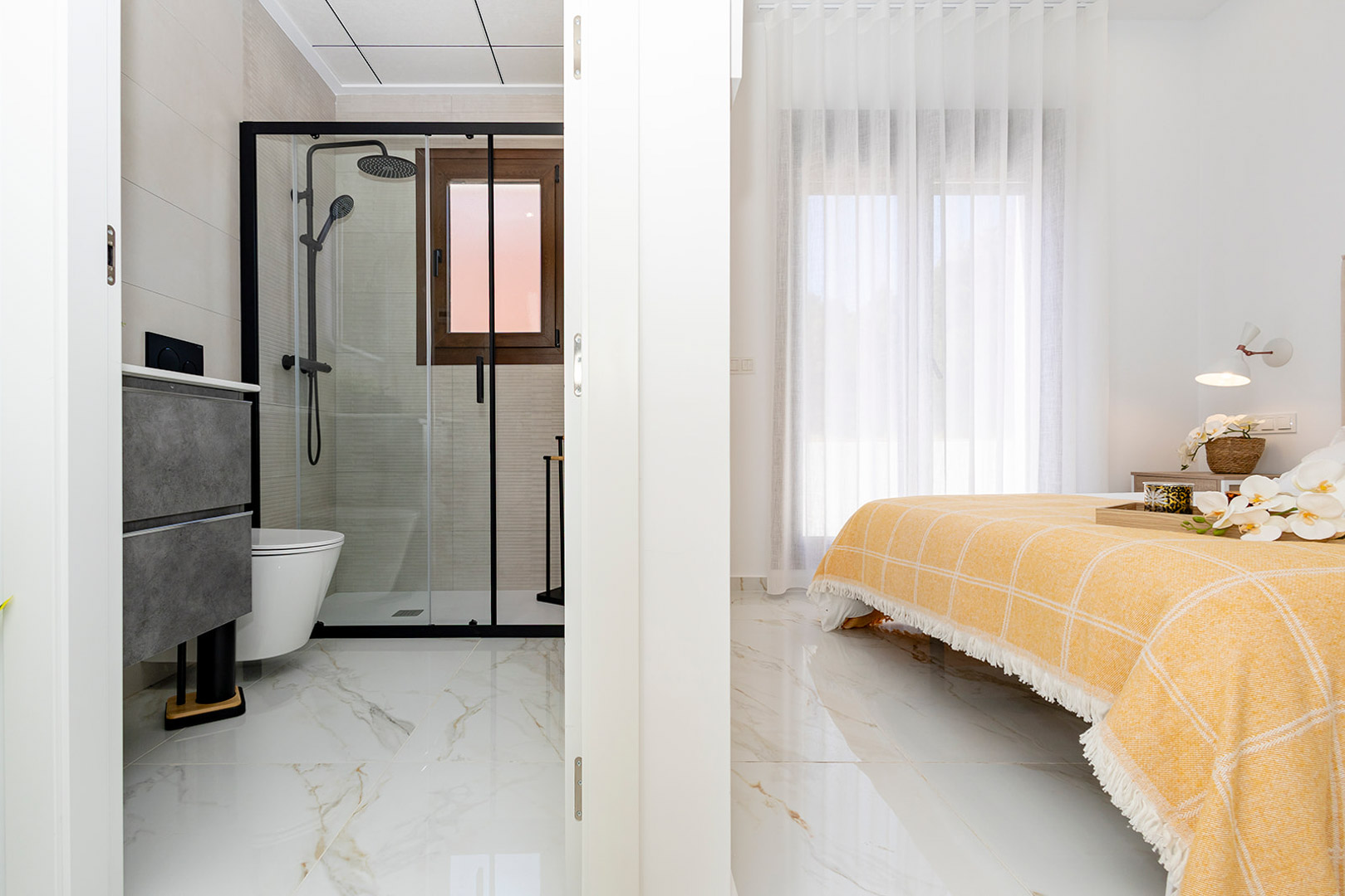 Bedroom featuring an integrated en-suite bathroom with marble-effect porcelain flooring and a walk-in shower with black profiles.