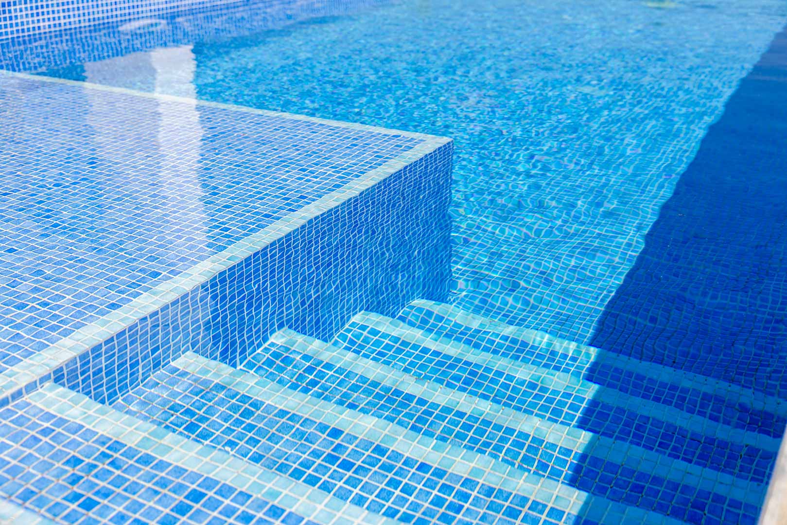 Close-up of the private swimming pool featuring blue mosaic tiling and submerged built-in steps, highlighting the water clarity and clean lines.